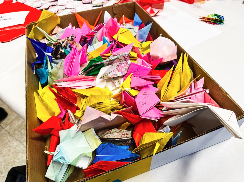 Paper flowers and cranes are placed in a box to be used in a ceremony to remember James Hatsuaki Wakasa's life. Wakasa was killed at Topaz War Relocation Center in 1943.