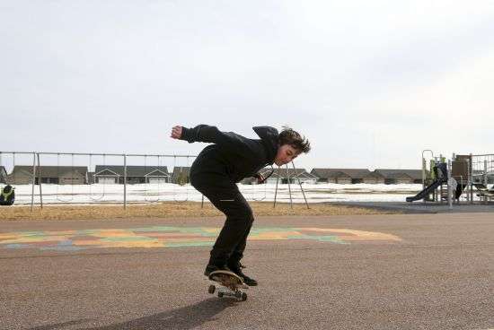 Asher Wilcox-Broekemeier, 13, practices with his skateboard at an elementary school playground after school hours on March 27 in Sioux Falls, S.D. Asher's parents have noticed his emotions stabilize through his treatment. “From a parent’s view, I see him as being able to be himself authentically, which is wonderful for him,” Elizabeth said.