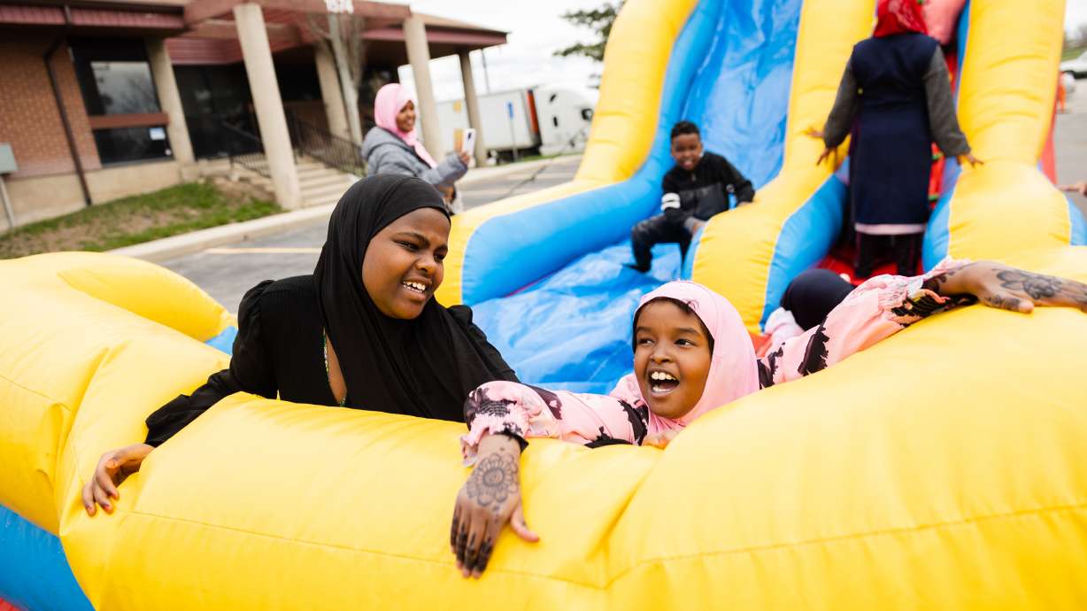 Filsan Salad, 10 years old, right, laughs while playing on an inflatable slide during the Eid al-Fitr celebration at Hartland Partnership Center in Salt Lake City on Saturday.