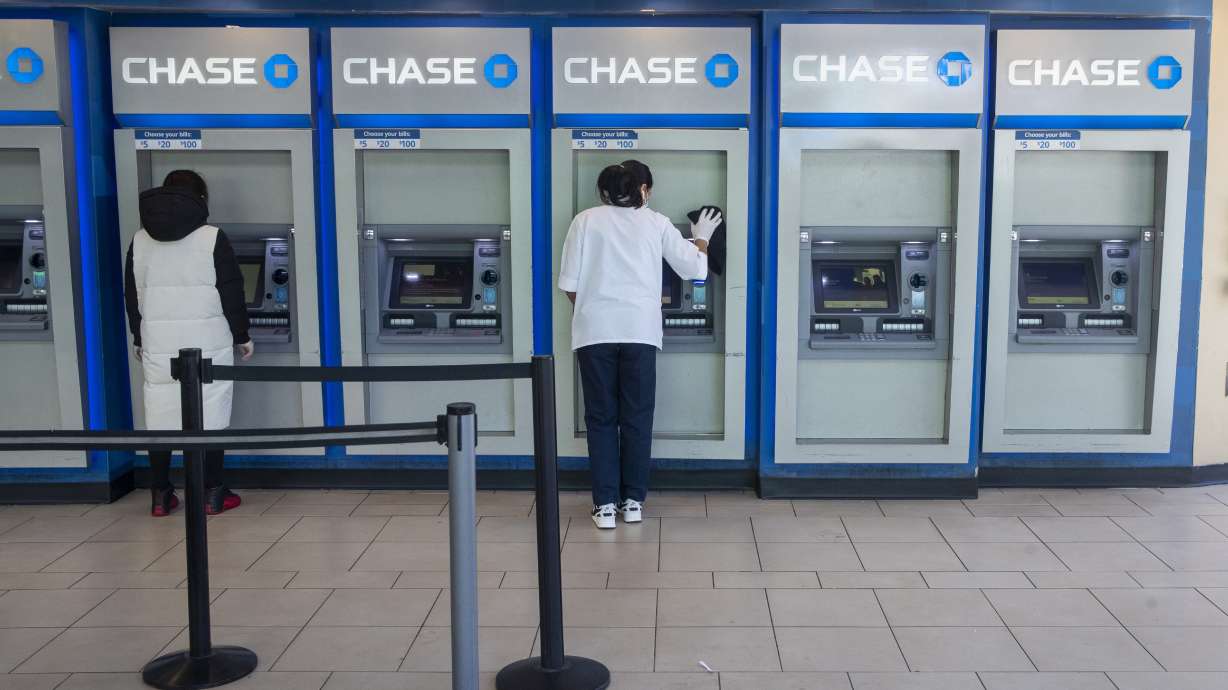 A worker, right, cleans an ATM as a customer uses another at a Chase branch in the Queens borough of New York on March 24, 2020. Banks are paying up for savers' deposits in a much bigger way than they have in more than a decade.