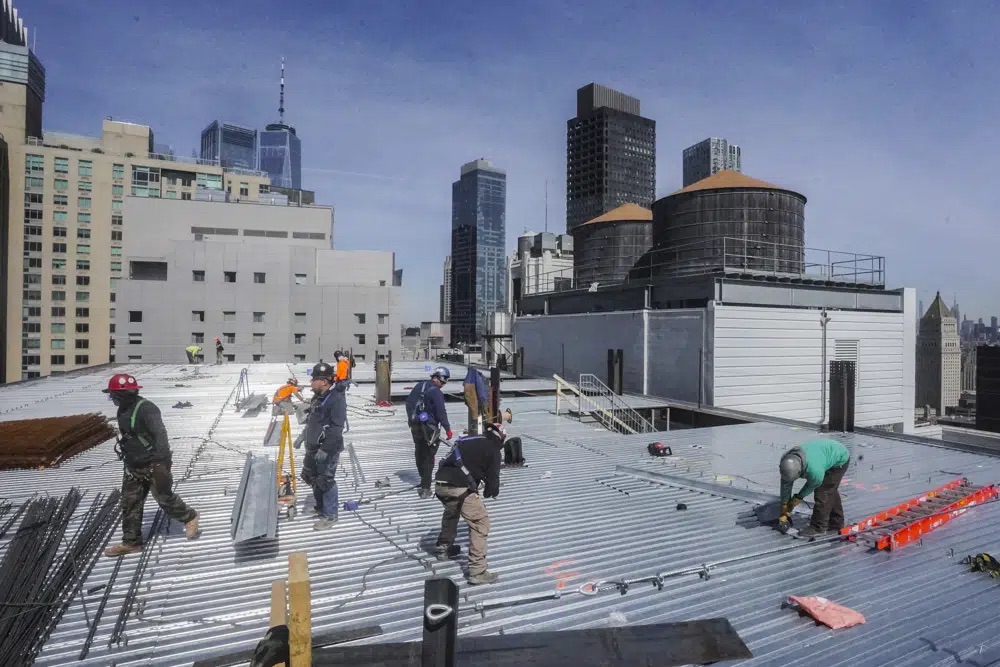Construction workers update the roofing on a high rise at 160 Water Street in Manhattan's financial district, for the building's conversion to residential apartments April 11 in New York. A growing number of developers are considering converting empty office towers into housing as part of an effort to revive struggling downtown business districts that emptied out during the pandemic.