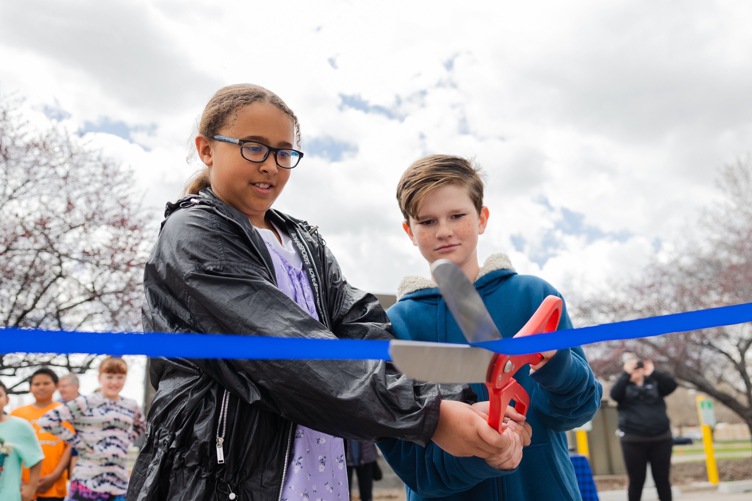 Zerrin Twibey, left and Zachary McEwen, right, students at Taylorsville Elementary School, cut the ribbon during a celebration of the completed solar panel project at the Taylorsville State Office Building in Taylorsville on Monday. 