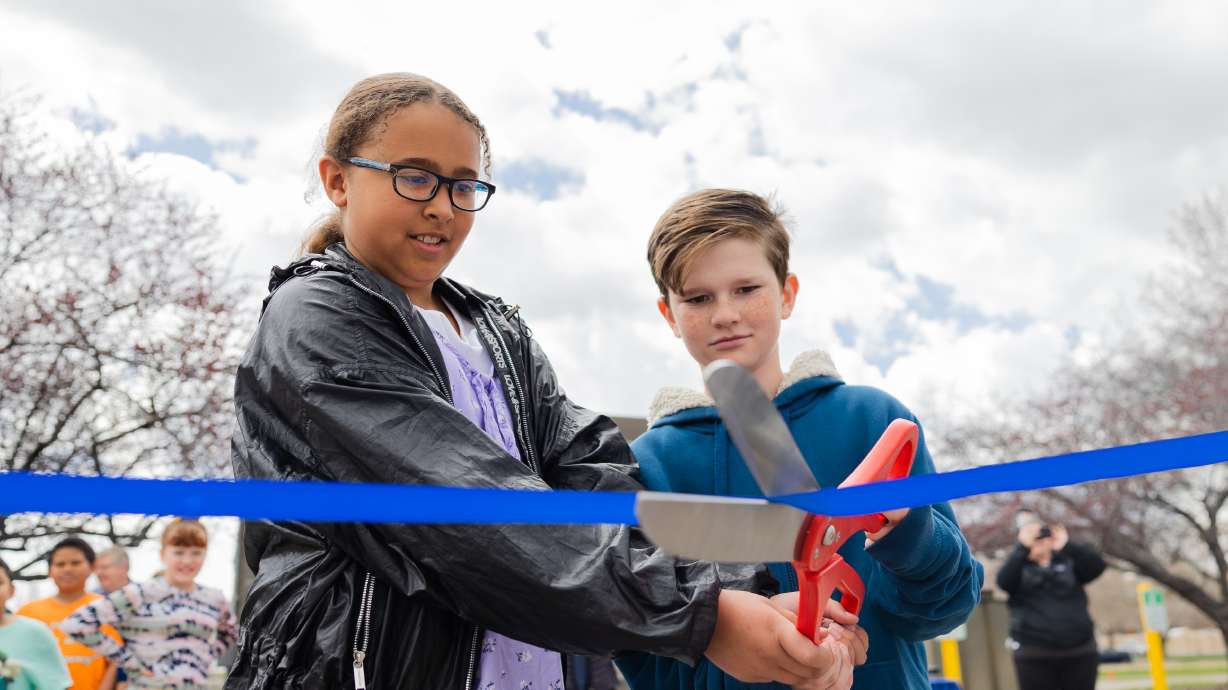 Zerrin Twibey, left and Zachary McEwen, right, students at Taylorsville Elementary School, cut the ribbon during a celebration of the completed solar panel project at the Taylorsville State Office Building in Taylorsville on Monday.