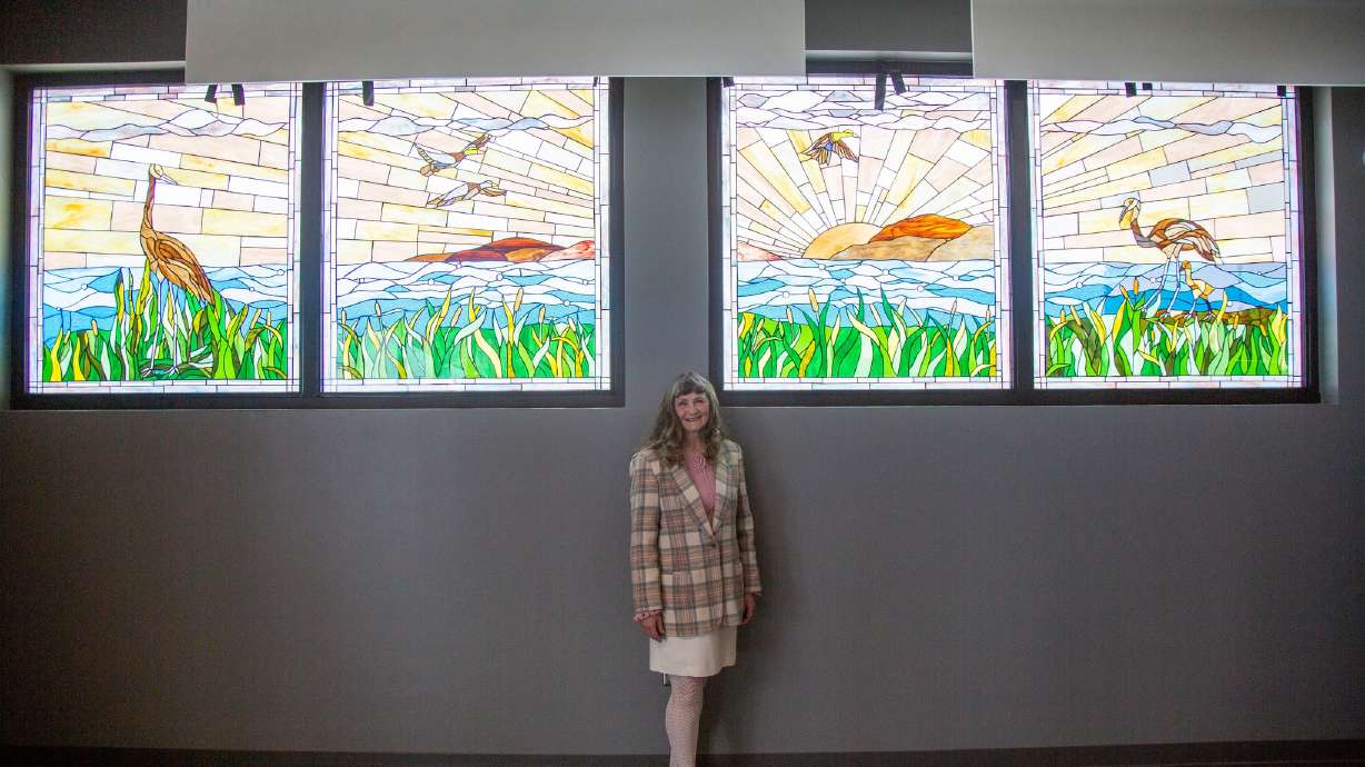 Provo artist Jeanne Gomm stands in front of her Utah Lake stained glass mural at the unveiling of the artwork at Provo Airport on April 5.