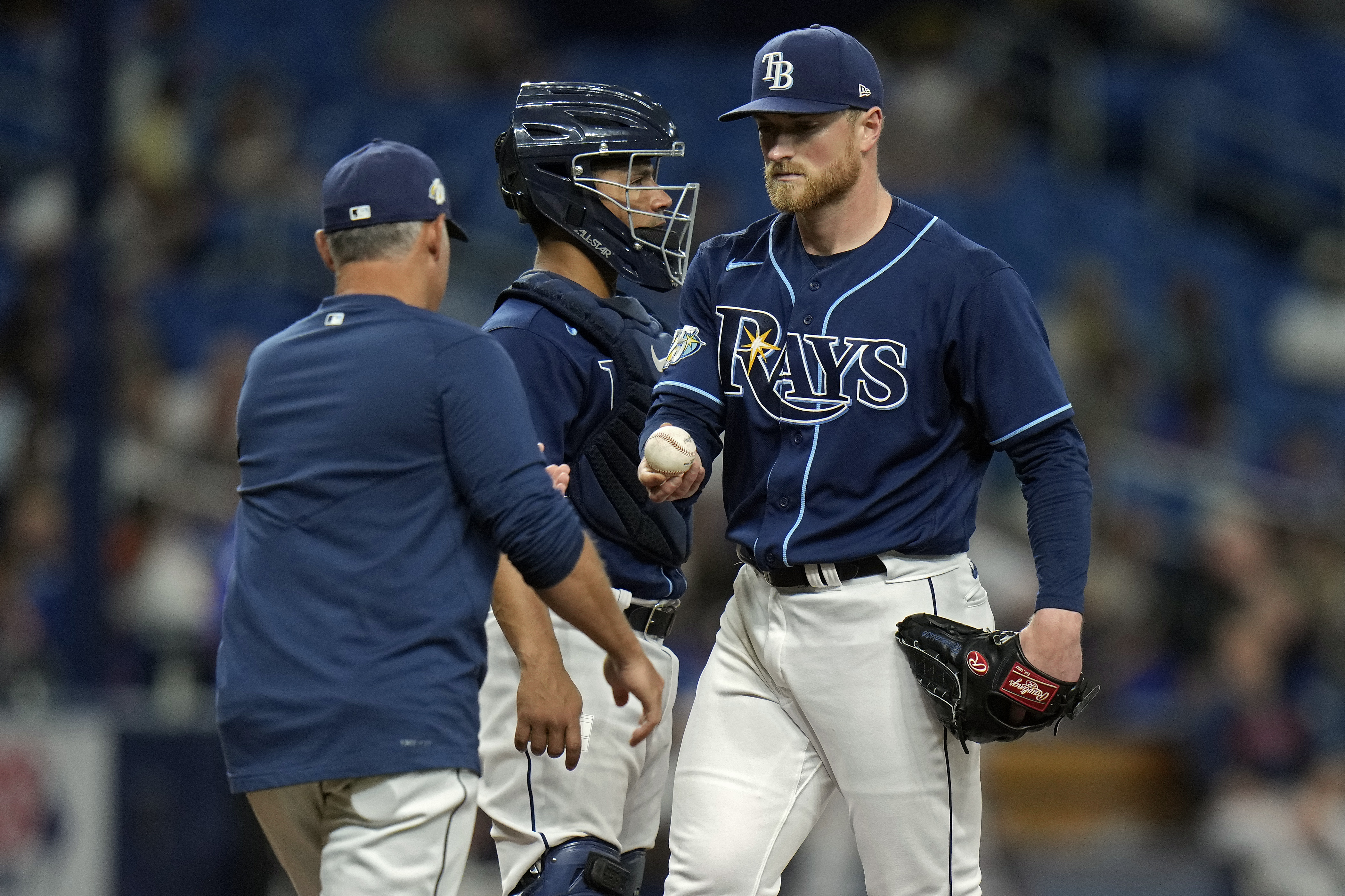 Tampa Bay Rays starting pitcher Drew Rasmussen, right, hands the ball to manager Kevin Cash, left, as he is taken out of the game against the Houston Astros during the fifth inning of a baseball game Tuesday, April 25, 2023, in St. Petersburg, Fla. Looking in is Rays' catcher Francisco Mejia. 