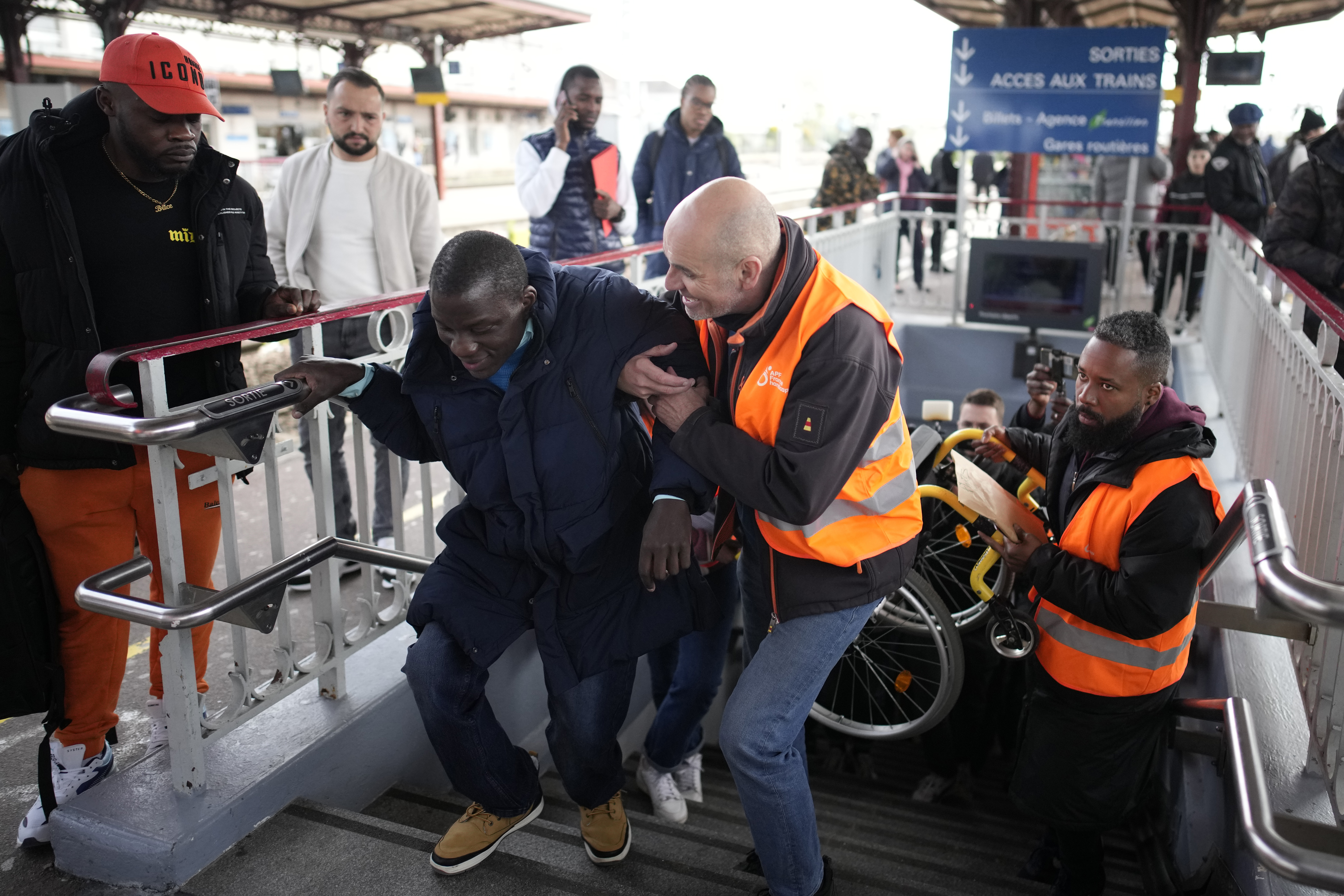 A disable man is helped climbing the stair to access the platform Wednesday, April 26, 2023 at the Melun train station, outside Paris. An influential disabled rights group in France is boycotting a conference on disability Wednesday with French President Emmanuel Macron, amid frustration at dismal accessibility for people in wheelchairs and with other mobility challenges -- and years of unmet promises to make things better ahead of the Paris 2024 Olympic and Paralympic Games. 