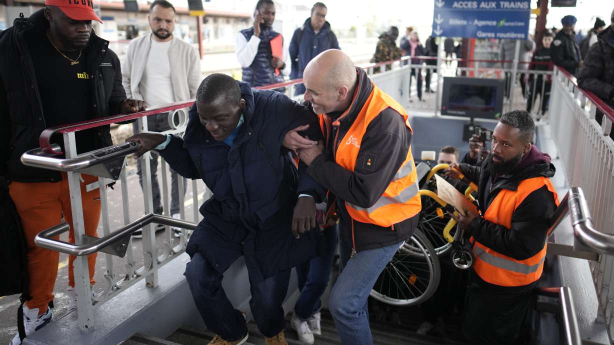 A disable man is helped climbing the stair to access the platform Wednesday, April 26, 2023 at the Melun train station, outside Paris. An influential disabled rights group in France is boycotting a conference on disability Wednesday with French President Emmanuel Macron, amid frustration at dismal accessibility for people in wheelchairs and with other mobility challenges -- and years of unmet promises to make things better ahead of the Paris 2024 Olympic and Paralympic Games.