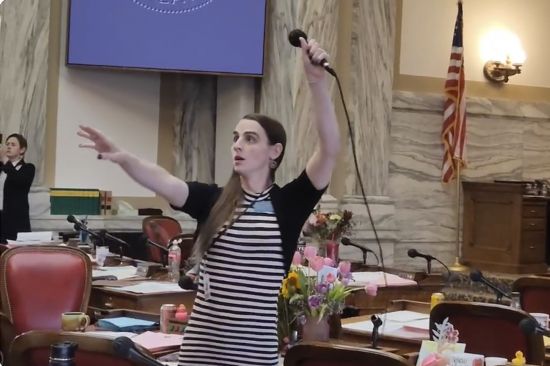 Montana Democratic Rep. Zooey Zephyr hoists a microphone into the air on Monday as her supporters interrupt proceedings in the state House by chanting "Let Her Speak!" in Helena, Mont. Republican leaders in the Legislature didn't let Zephyr, who is transgender, speak on the floor for the third consecutive day because she refuses to apologize for calling GOP lawmakers out for supporting a ban on gender-affirming care.