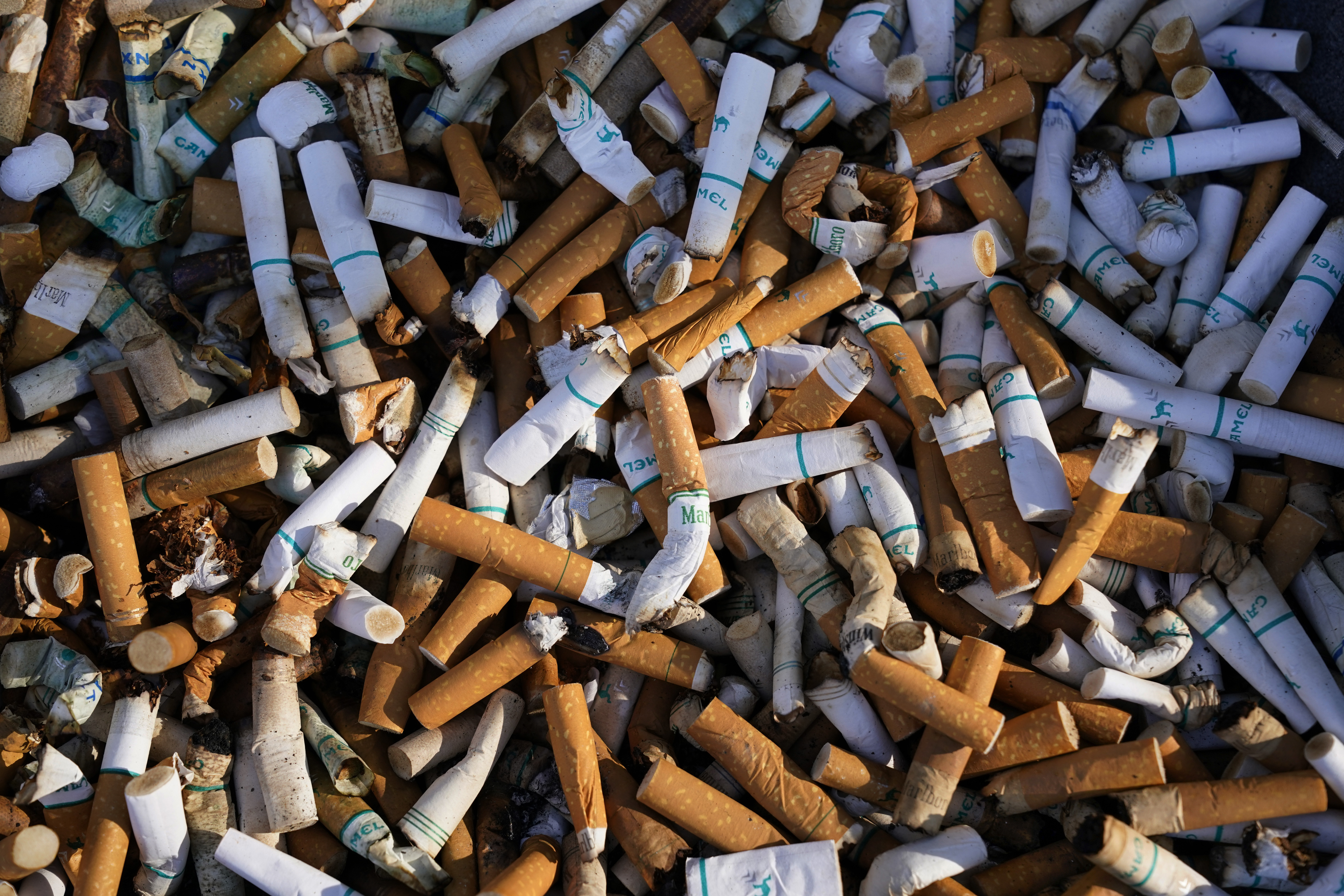 Cigarette butts fill a smoking receptacle outside a federal building in Washington, April 15, 2021. According to government survey data released Thursday, U.S. adults are smoking less. 
