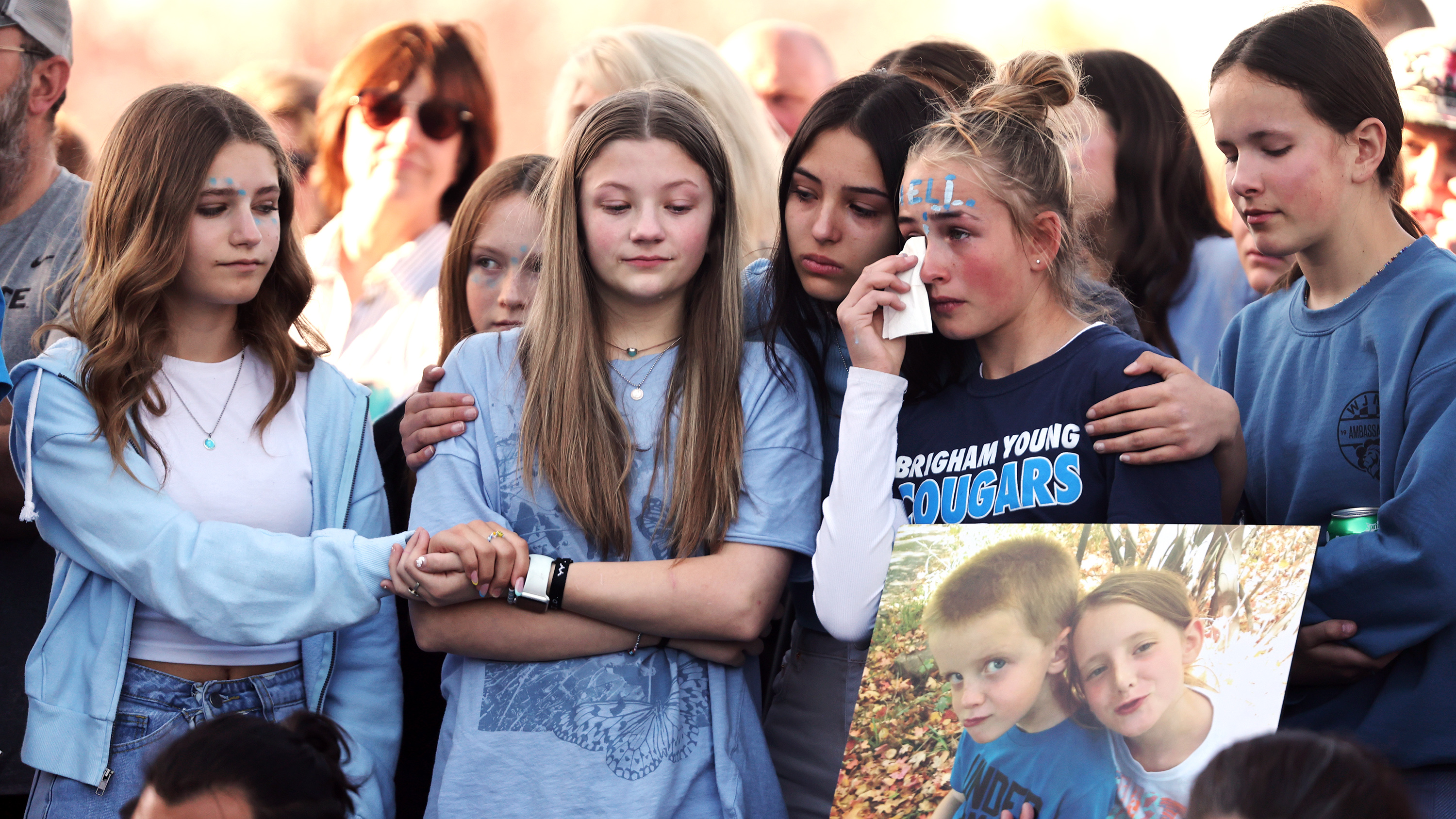 Young girls group together for comfort as they join a large group of people gathered on Wednesday, April 26, 2023 in West Jordan at 9000 South and 1510 West where one year ago 13-year-old Eli Mitchell was killed by a drunk driver.