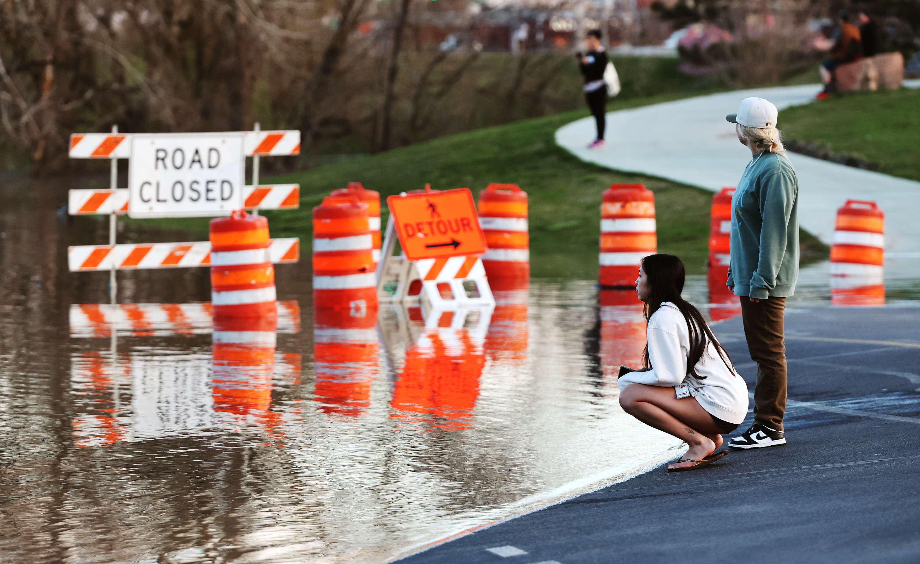 Alanna Lee and Kaitlyn Cunningham look at the ducks as flood water overtakes the road at Sugar House Park on Wednesday. The park remains closed to vehicles because of flooding.