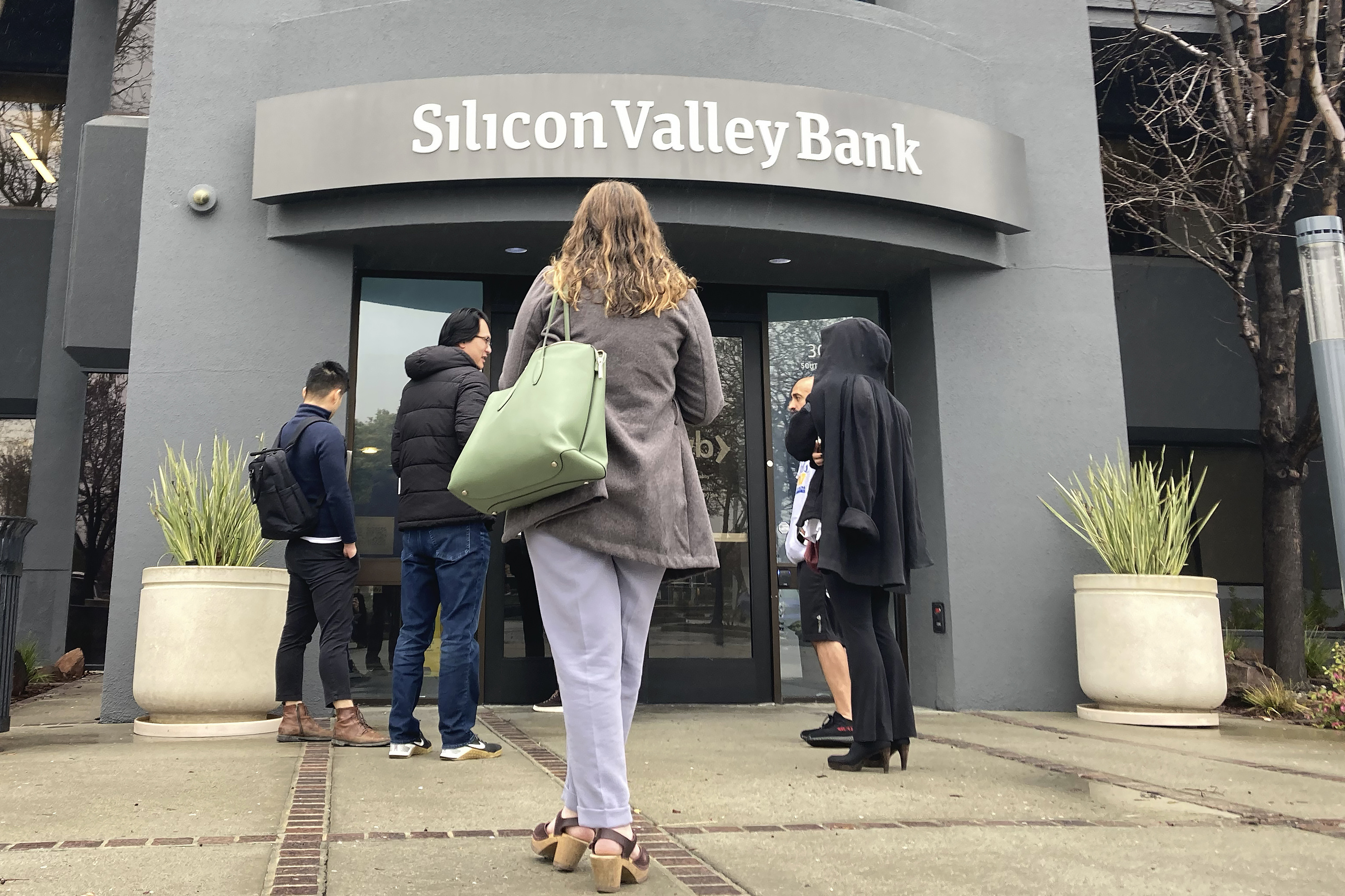 People stand outside a Silicon Valley Bank branch in Santa Clara, Calif., March 10. The bank failed due to a combination of extremely poor bank management, weakened regulations and lax government supervision, the Federal Reserve said Friday.