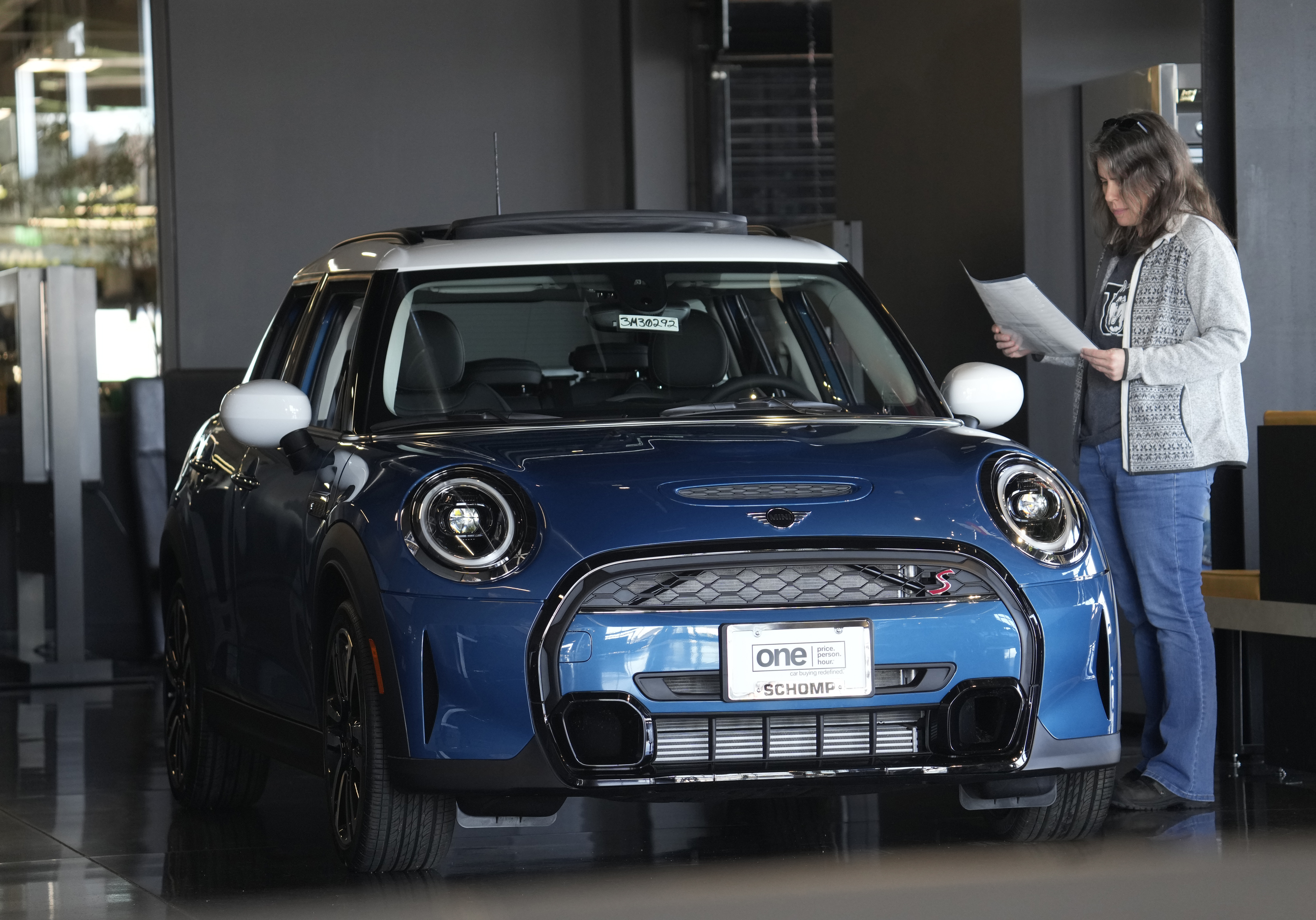 A potential buyer looks over an 2023 Cooper S sedan Feb. 17, in Highlands Ranch, Colo. On Friday, the Commerce Department issued its March report on consumer spending. 