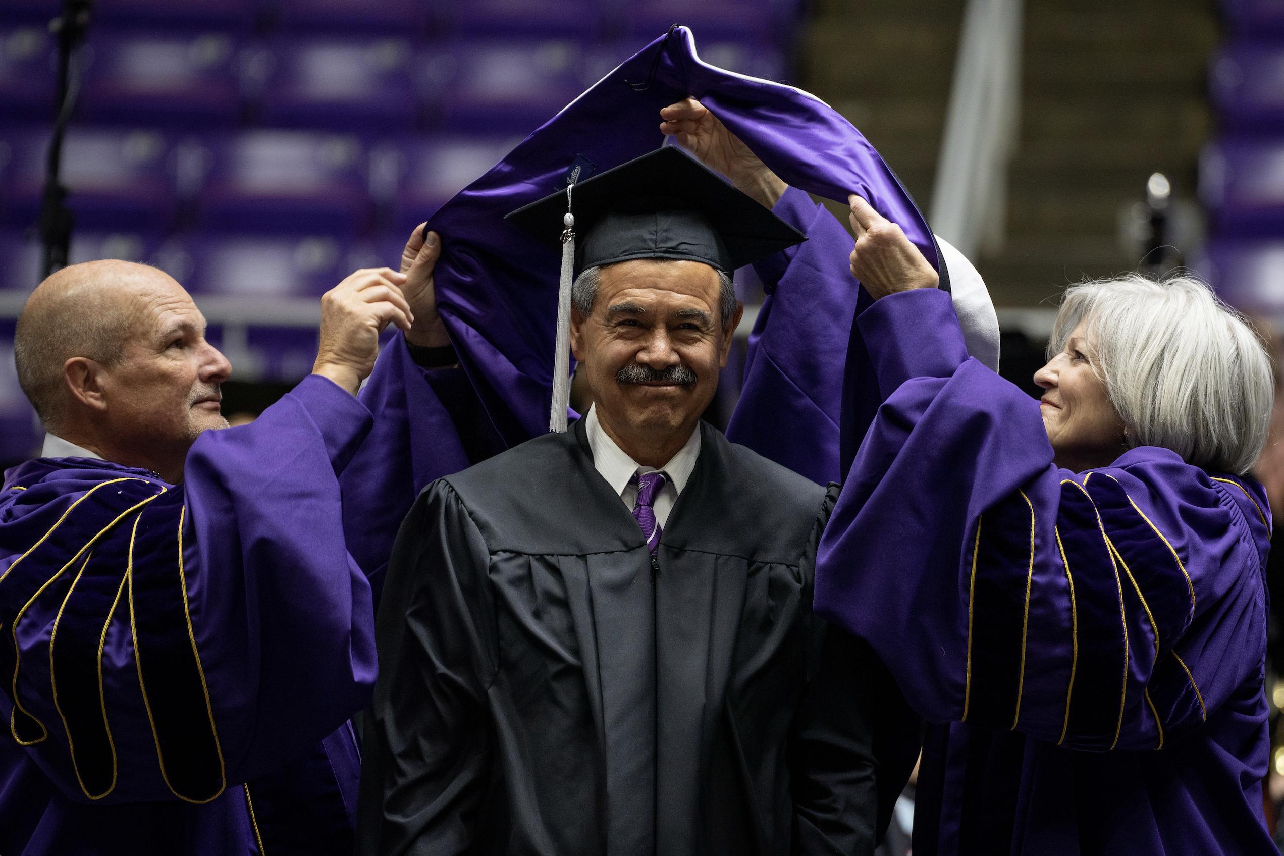 Javier Chavez Sr. receives a doctoral hood at the Weber State University commencement ceremony on Friday. Chavez was one of four individuals who were awarded doctoral degrees. 