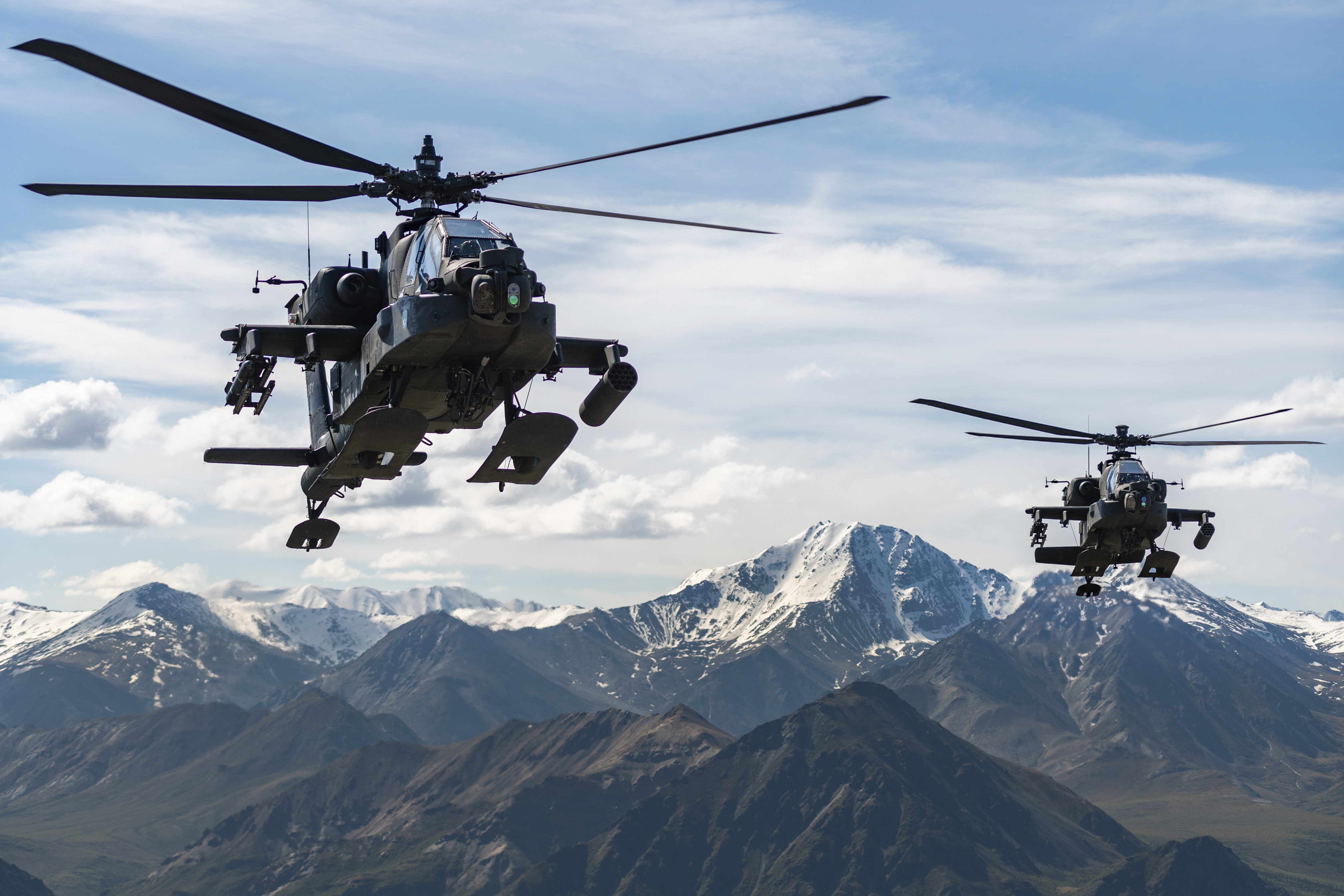 An AH-64D Apache Longbow attack helicopters fly over a mountain range near Fort Wainwright, Alaska, on June 3, 2019. The U.S. Army says two Army helicopters similar to the ones in this picture crashed Thursday near Healy, Alaska, killing three soldiers and injuring a fourth.
