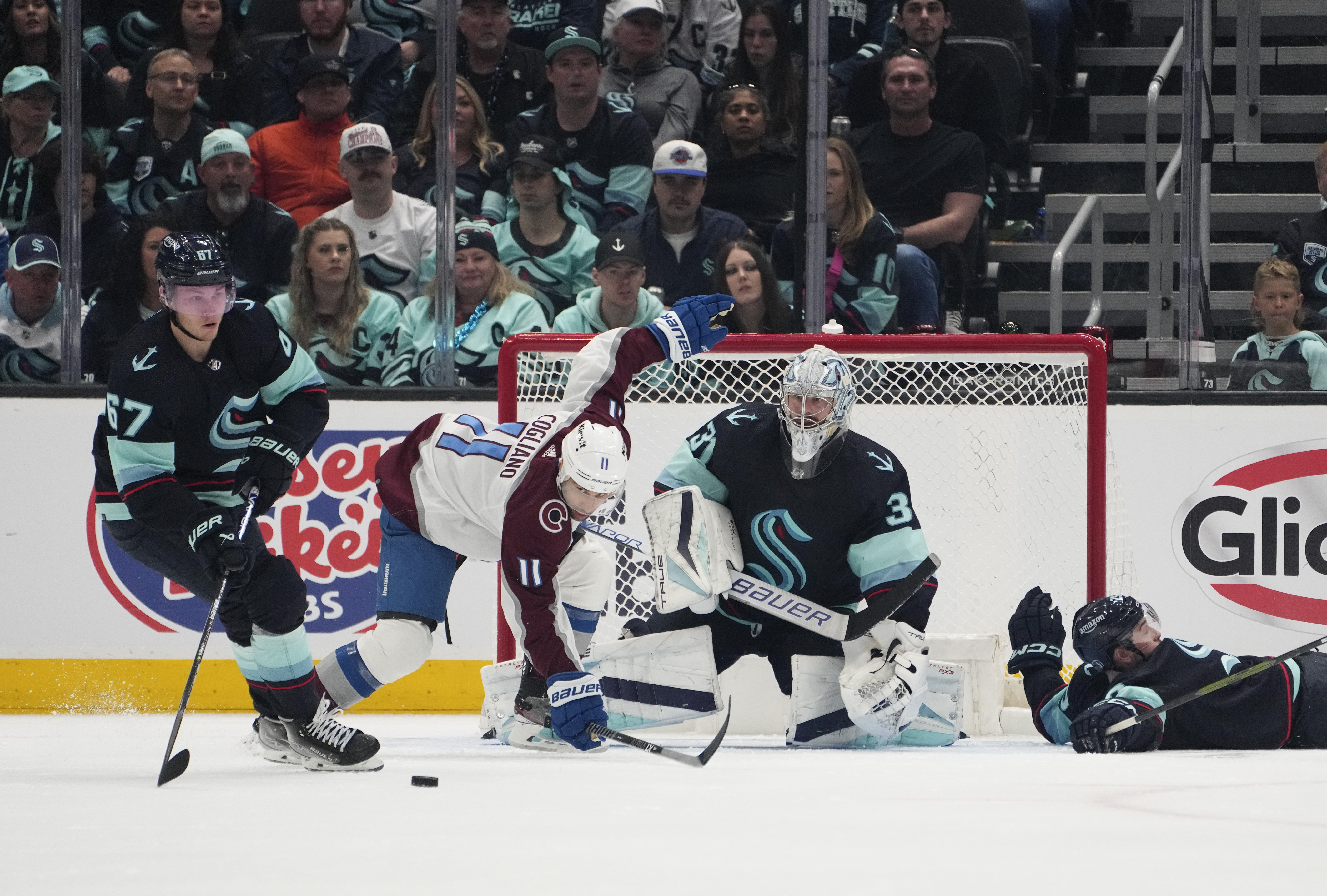 Seattle Kraken center Morgan Geekie (67) clears the puck as Colorado Avalanche center Andrew Cogliano (11) trips near the goal and Kraken goaltender Philipp Grubauer (31) watches during the third period of Game 6 of an NHL hockey Stanley Cup first-round playoff series Friday, April 28, 2023, in Seattle. The Avalanche won 4-1. 