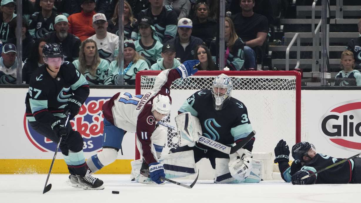Seattle Kraken center Morgan Geekie (67) clears the puck as Colorado Avalanche center Andrew Cogliano (11) trips near the goal and Kraken goaltender Philipp Grubauer (31) watches during the third period of Game 6 of an NHL hockey Stanley Cup first-round playoff series Friday, April 28, 2023, in Seattle. The Avalanche won 4-1.
