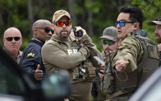 Authorities from multiple agencies work at a location where law enforcement believe they have cornered a suspect who allegedly shot and killed five people in a house the night before, Saturday in unincorporated San Jacinto County, Texas.