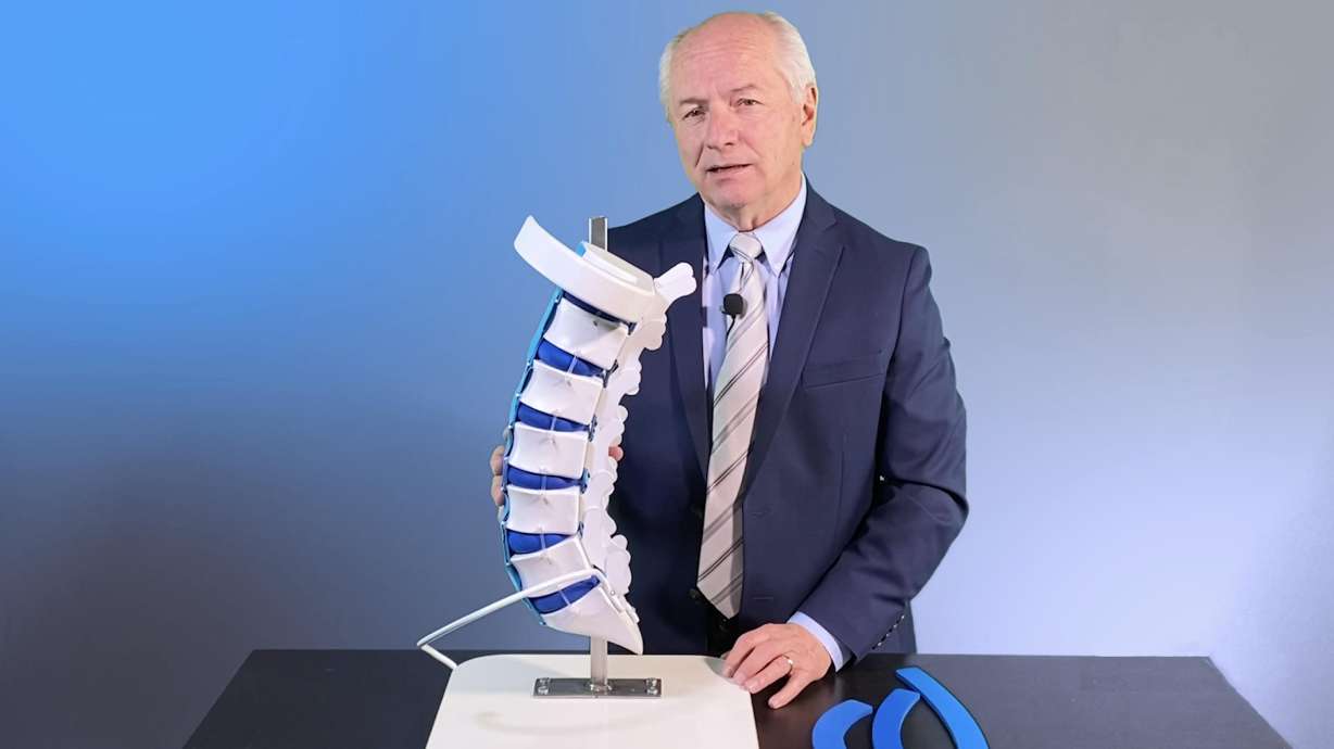 Upright Spine Solutions Clinical Research Director Michael Halliday with a model of a spine.
