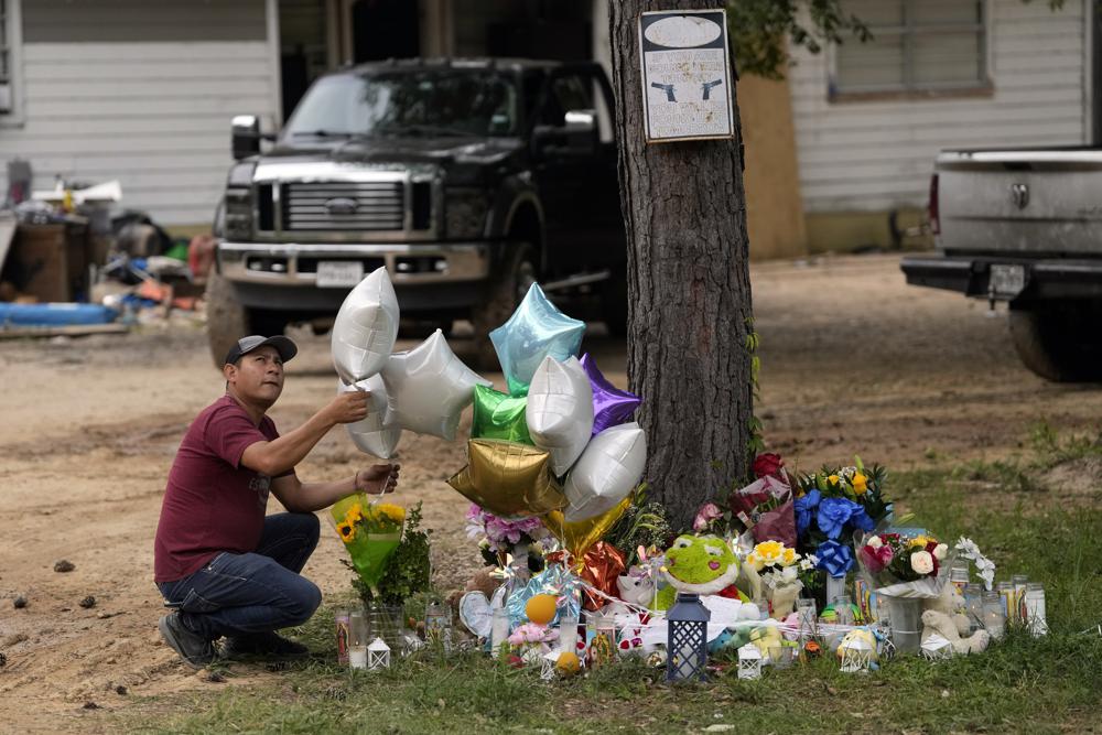 A man releases a balloon from the makeshift memorial outside the victims' home Tuesday where a mass shooting occurred Friday, in Cleveland, Texas.