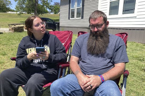 Justin Webster and his wife, Ashleigh, sit outside their Henryetta, Oklahoma, home on Tuesday. The couple's daughter, Ivy, 14, was among seven people found slain at a home in Henryetta on Monday.