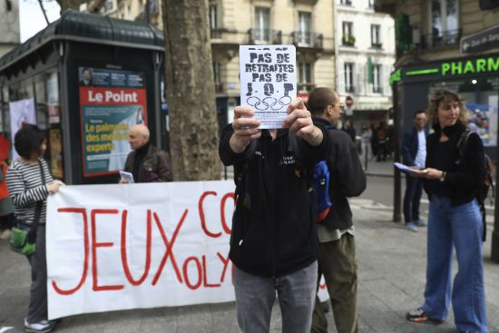 Activists stage a protest against Paris 2024 Olympics, one showing a leaflet reading "No withdrawal of the pension reform, no Olympic Games," in Paris, Monday. Olympic contestation is picking up online and starting to spill onto streets because protesters are linking the Paris Games to unpopular pension reforms pushed through by French President Emmanuel Macron.