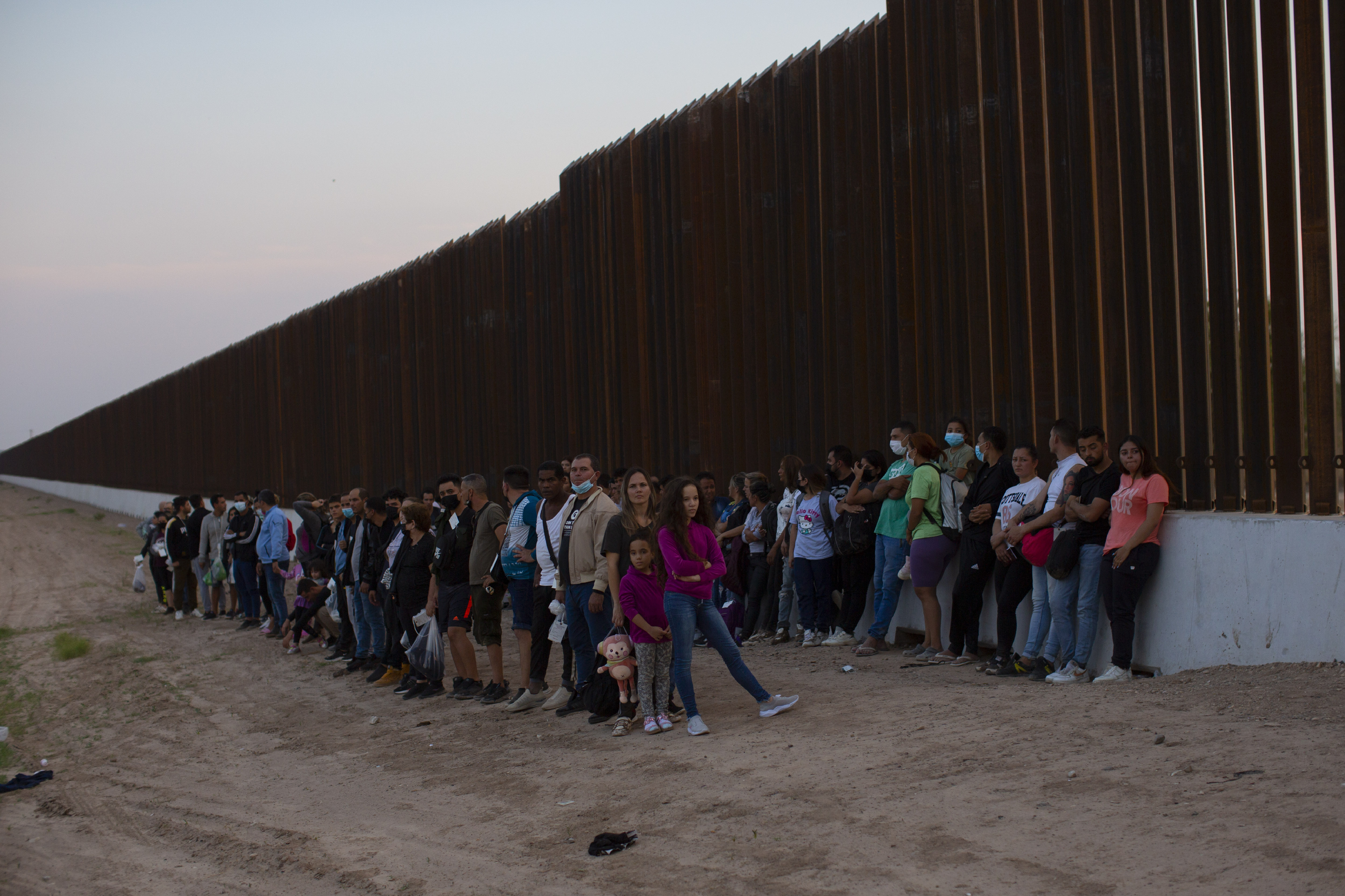 A group of migrants stand next to the border wall in Eagle Pass, Texas, on May 21, 2022. An expected surge in migration at the end of a pandemic-era immigration policy on May 11 is the latest border development that will likely impact Utah.