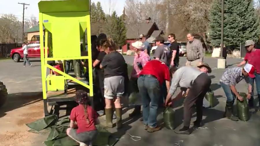 Volunteers surround a sandbagging machine in the Ogden Valley that is churning out fillled and tied bags by the hundreds. These volunteers joined forces to fill thousands of sandbags thanks to a key donation from a Huntsville man.