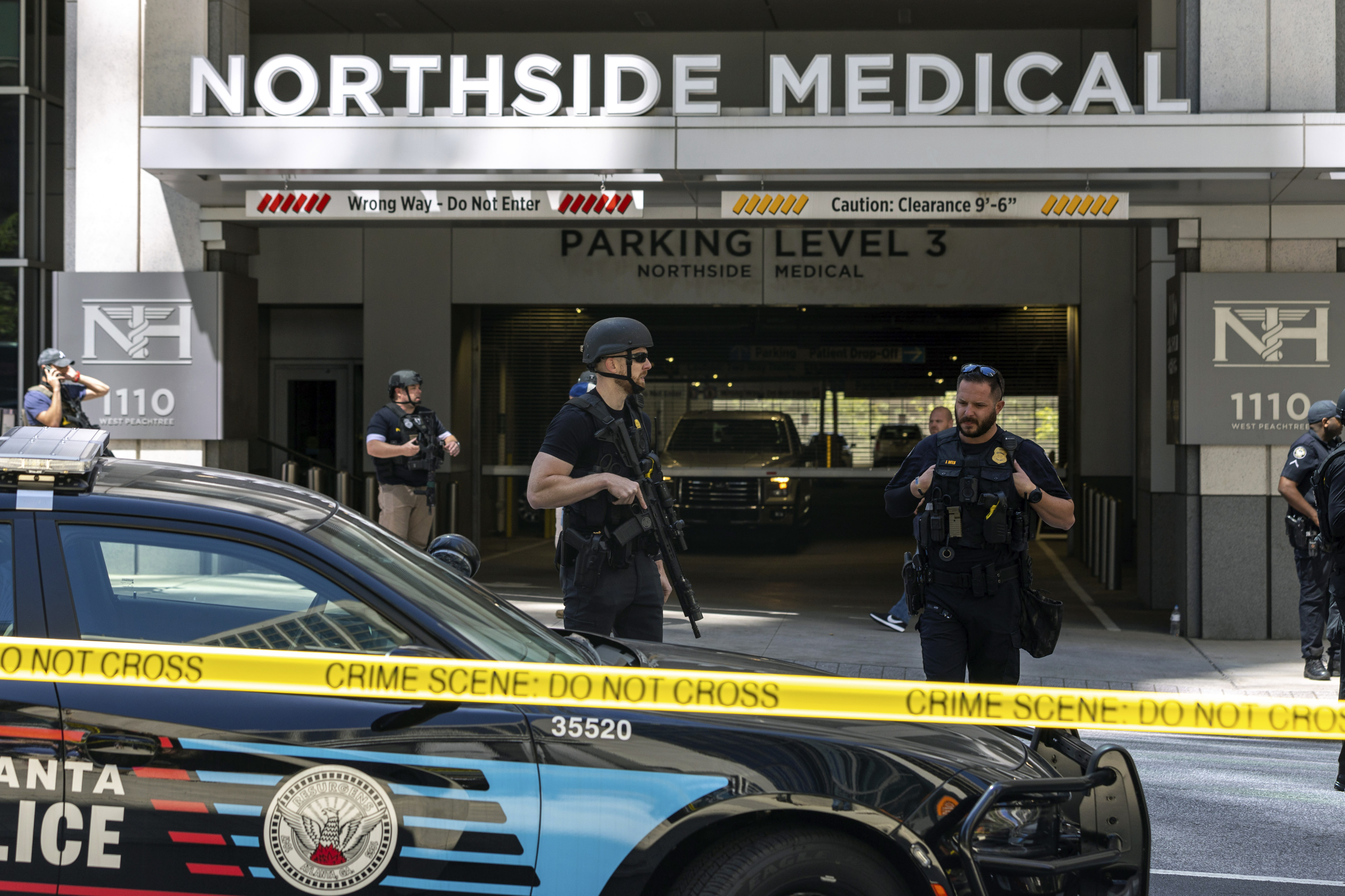 Law enforcement officers stand Northside Hospital Midtown medical office building, where five people were shot, Wednesday in Atlanta. Authorities swarmed the city’s bustling midtown neighborhood in search of the 24-year-old suspect. 