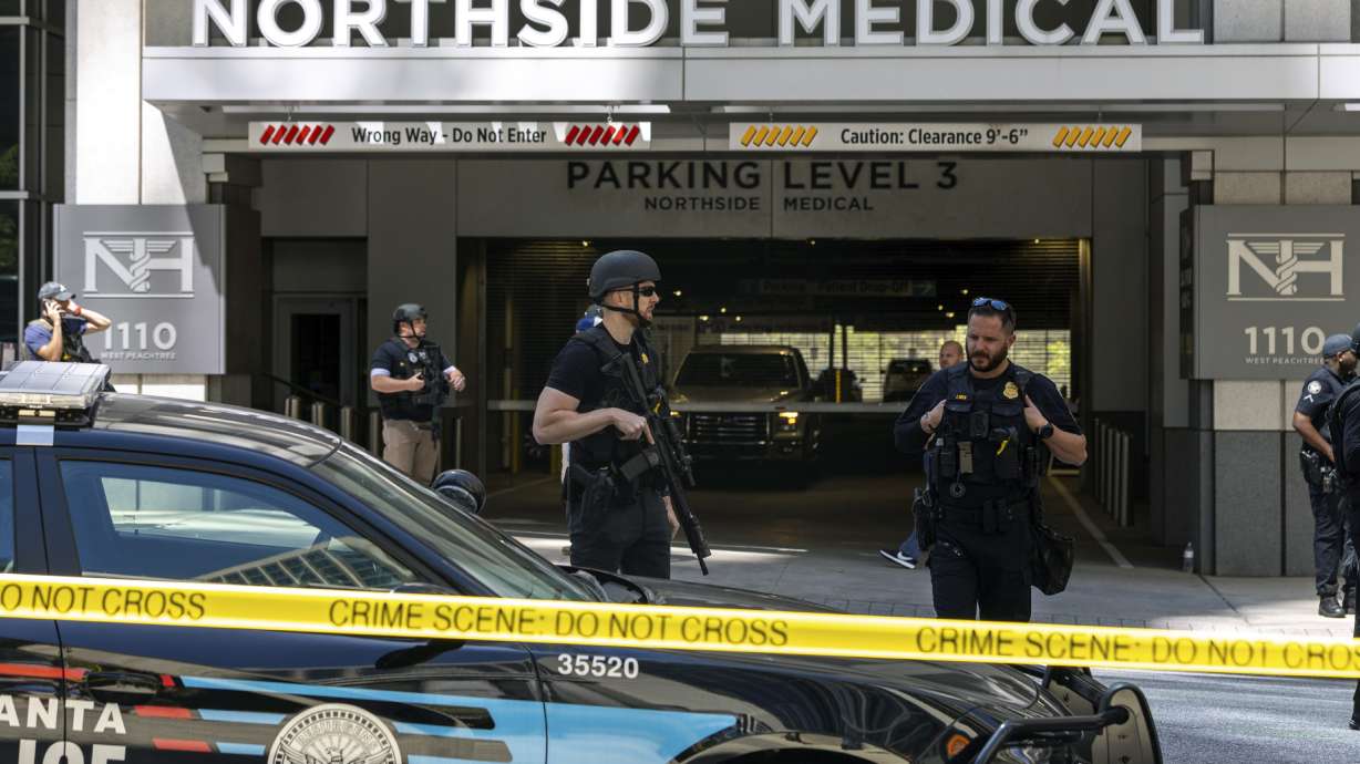 Law enforcement officers stand Northside Hospital Midtown medical office building, where five people were shot, Wednesday in Atlanta. Authorities swarmed the city’s bustling midtown neighborhood in search of the 24-year-old suspect.