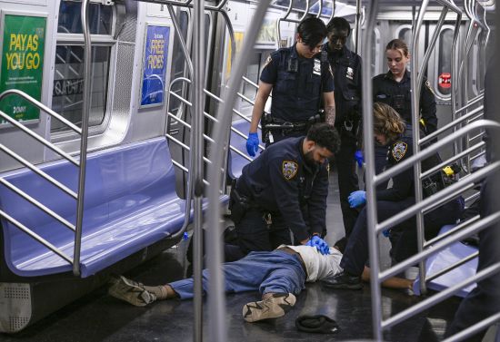 New York police officers administer CPR to a man at the scene where a fight was reported on a subway train, Monday in New York.