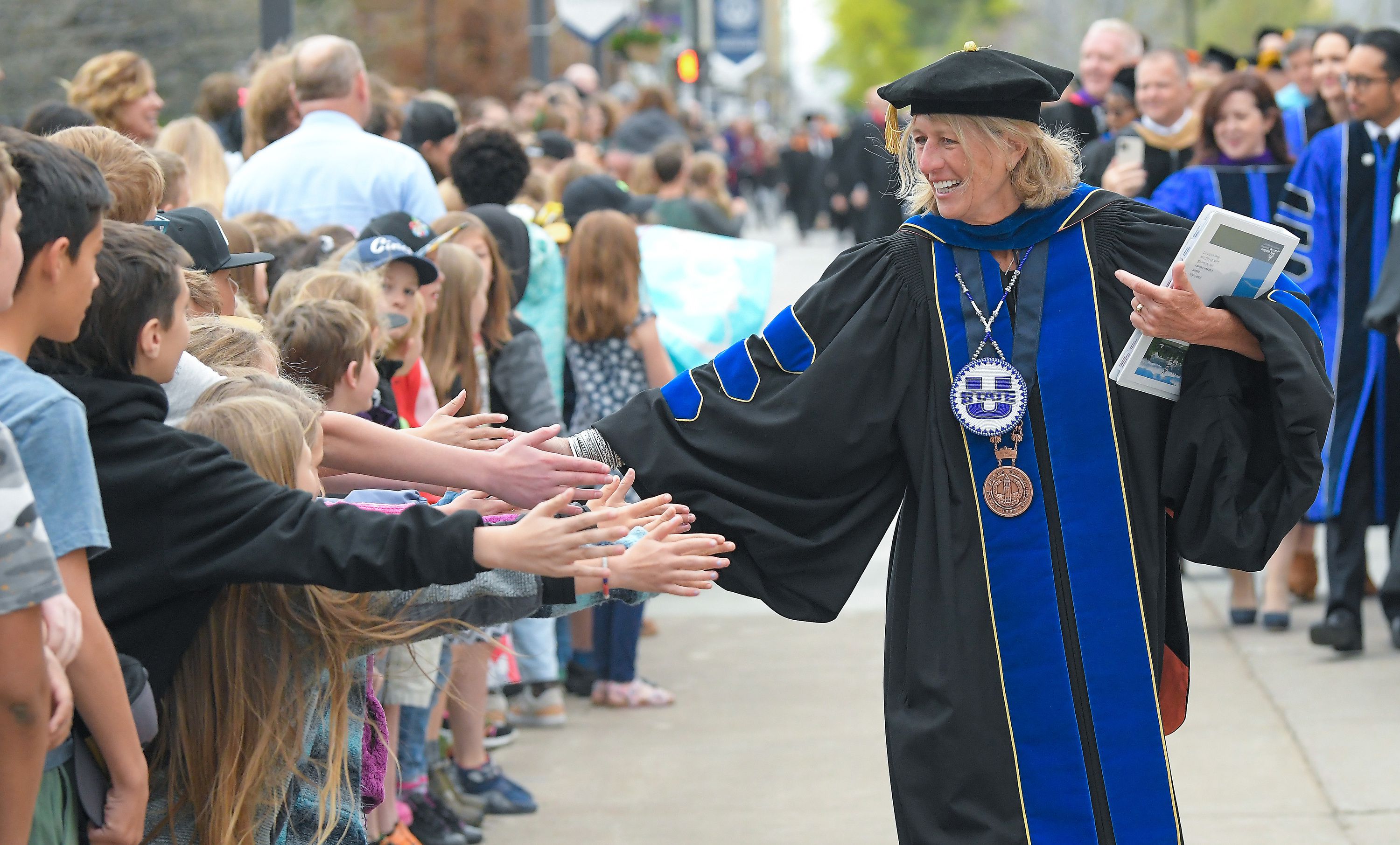 President Noelle Cockett celebrates with elementary school students during an academic procession across campus at Utah State University’s commencement ceremony on Thursday in Logan.