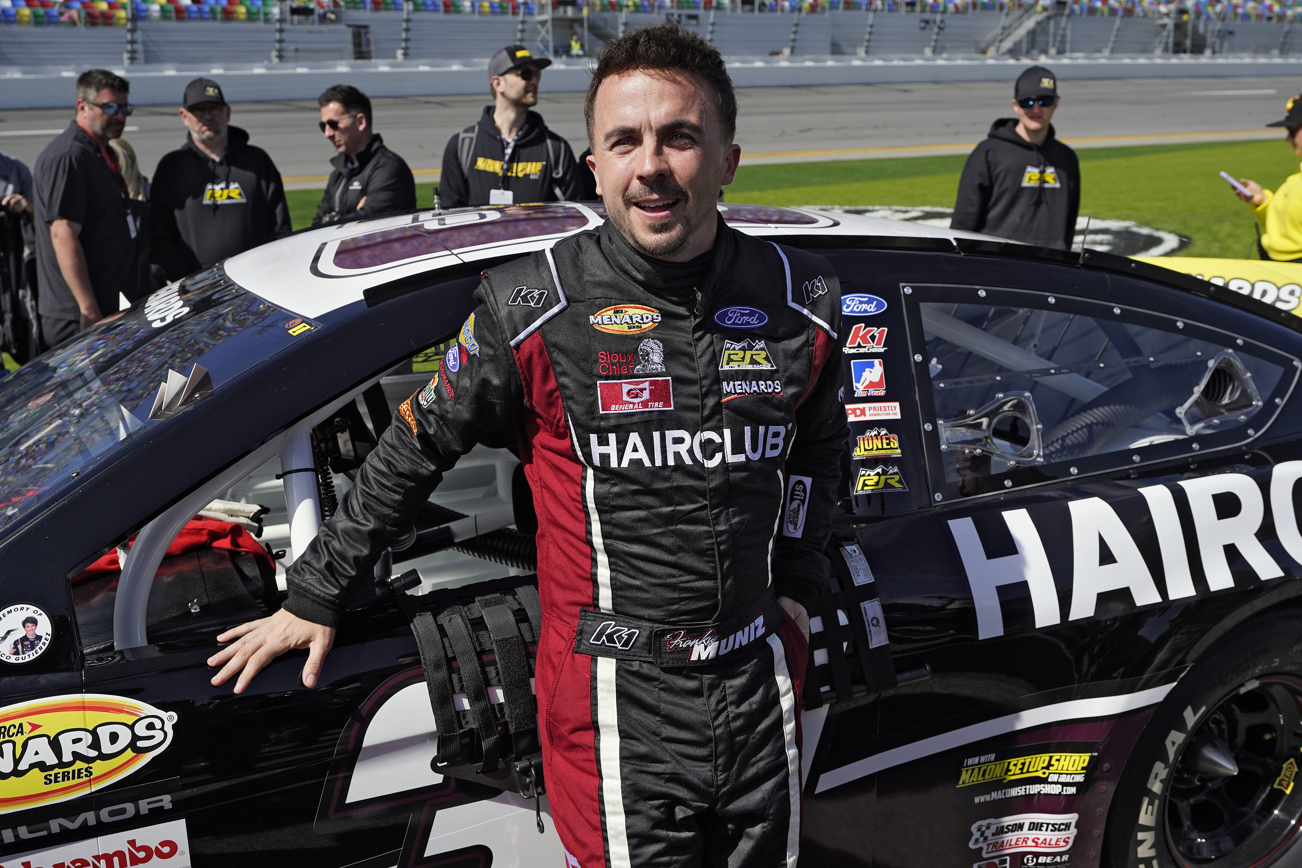 FILE - Actor turned race car driver Frankie Muniz leans on his car before the ARCA 200 auto race Feb. 18, 2023, at Daytona International Speedway in Daytona Beach, Fla. Muniz is the surprising points leader in the ARCA Series heading into Saturday’s race at Kansas Speedway in his first full season in stock car racing. 