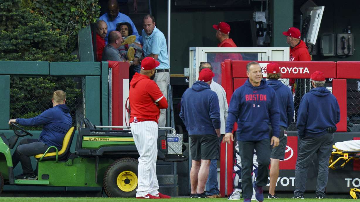 A fan, who fell into the Boston Red Sox bullpen, is brought down by the medical staff during the first inning of a baseball game against the Philadelphia Phillies, Friday, May 5, 2023, in Philadelphia.