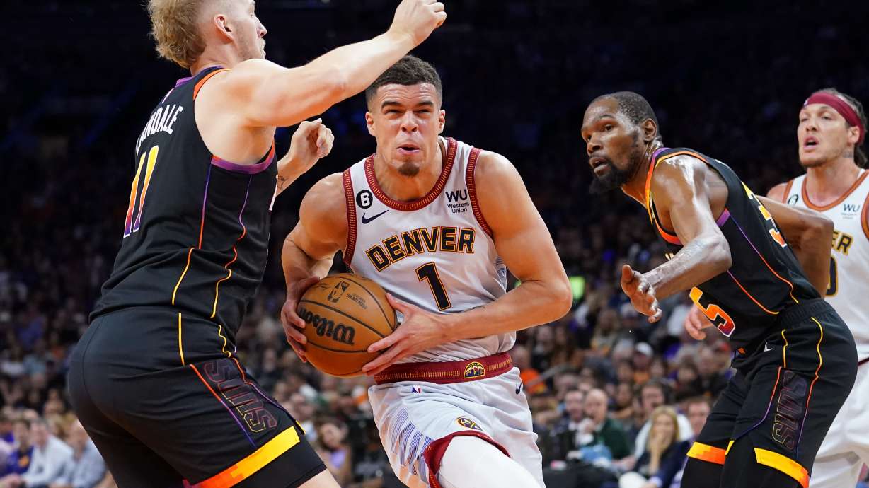 Denver Nuggets forward Michael Porter Jr. (1) drives between Phoenix Suns center Jock Landale, left, and forward Kevin Durant, right, during the second half of Game 3 of an NBA basketball Western Conference semifinal game, Friday, May 5, 2023, in Phoenix. The Suns defeated the Nuggets 121-114.