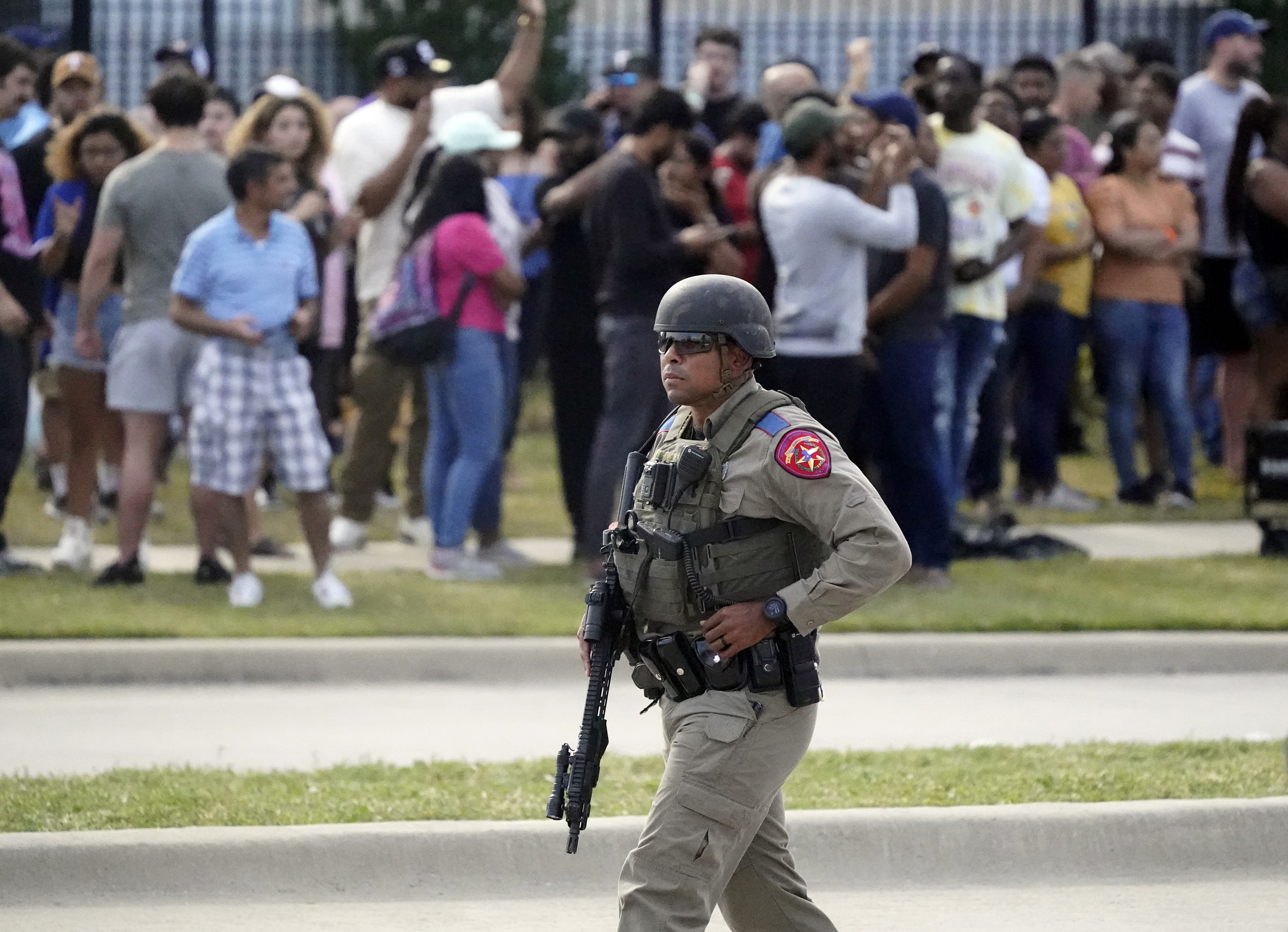 A law enforcement officer walks as people are evacuated from a shopping center where a shooting occurred May 6, in Allen, Texas. 