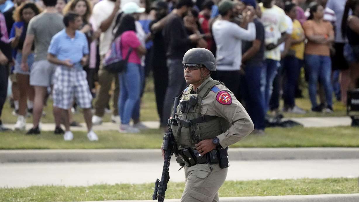 A law enforcement officer walks as people are evacuated from a shopping center where a shooting occurred May 6, in Allen, Texas.