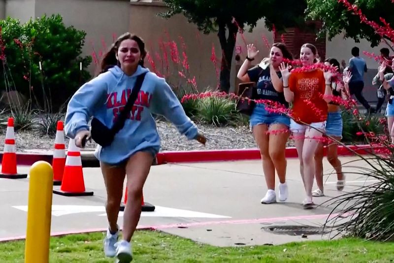 A girl runs as other shoppers leave with their hands up after police responded to a gunman who shot and killed eight people and wounded at least seven others at Allen Premium Outlets mall north of Dallas, in Allen, Texas, Saturday.