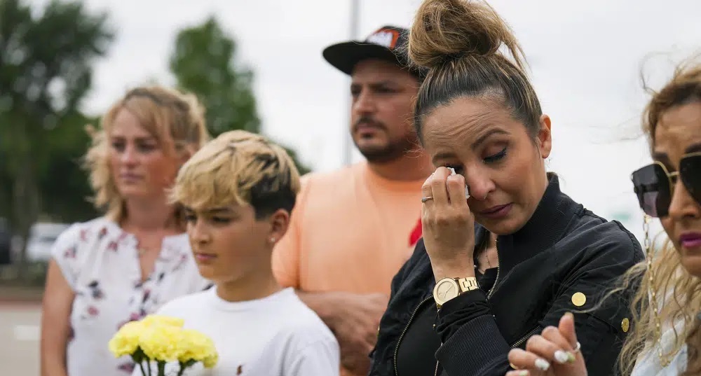 Sara Tabatabaie wipes away a tear at a memorial outside an entrance to the parking lot of the mall a day after a mass shooting at Allen Premium Outlets on Sunday in Allen, Texas. 