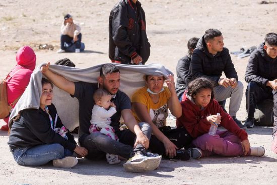 A migrant family sits in the heat between primary and secondary border fences as the United States prepares to lift COVID-19 restrictions that have blocked migrants at the U.S.-Mexico border from seeking asylum since 2020 near San Diego, California, U.S., May 8, 2023.