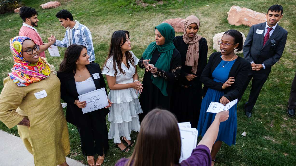 Graduates accept certificates of graduation from director of Elizabeth Zenger during the One Refugee graduation celebration at the Garden Place at Heritage Park in Salt Lake City on Monday.