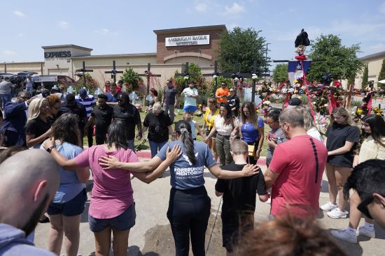 A large group of visitors are led in prayer at a makeshift memorial by the mall where several people were killed, Monday in Allen, Texas.
