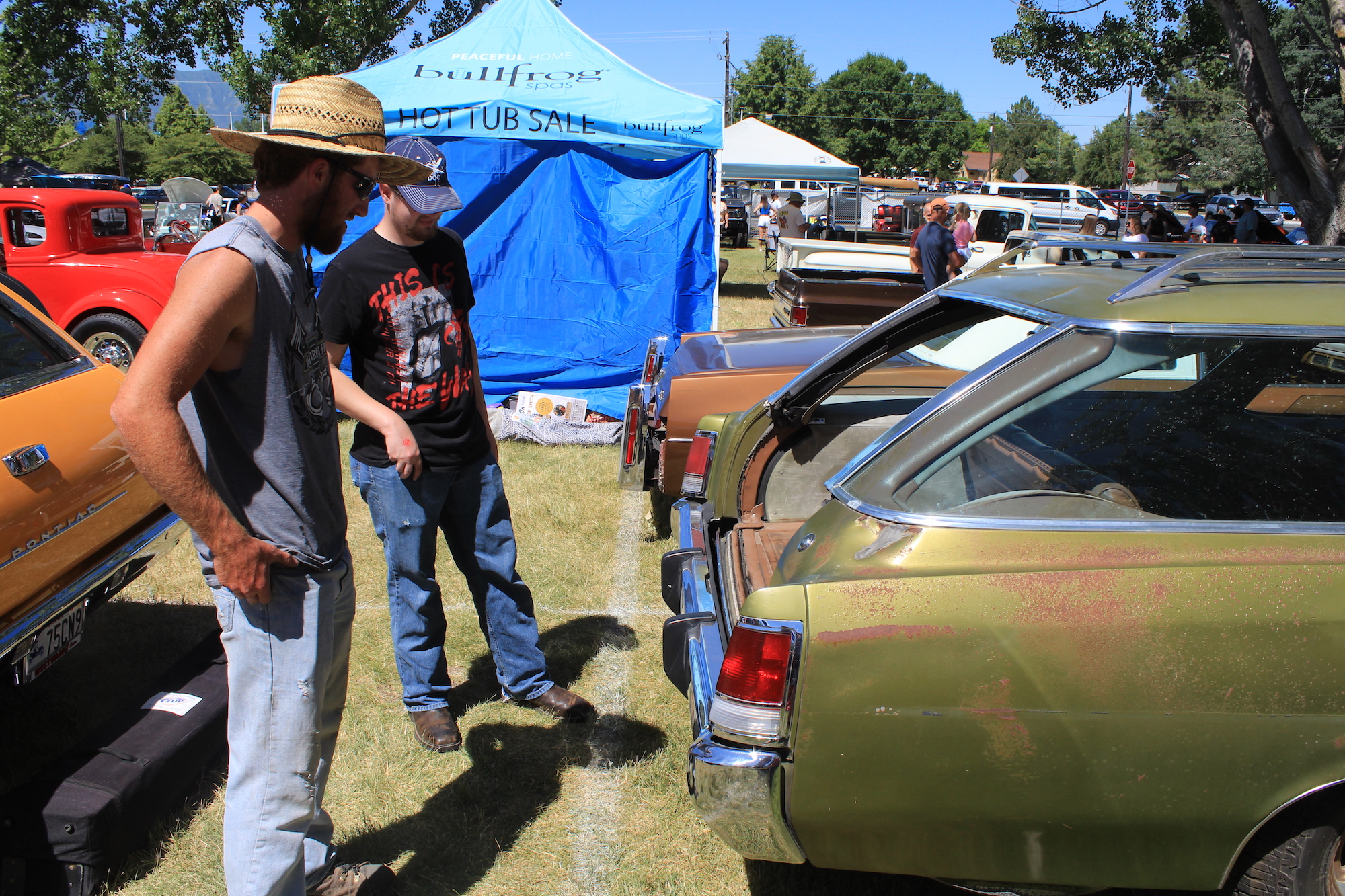 Gabe Kuszmaul (in straw hat) shows a fan the tailgate of his 1974 Pontiac wagon. The glass slides into the roof, the gate drops below bumper level.