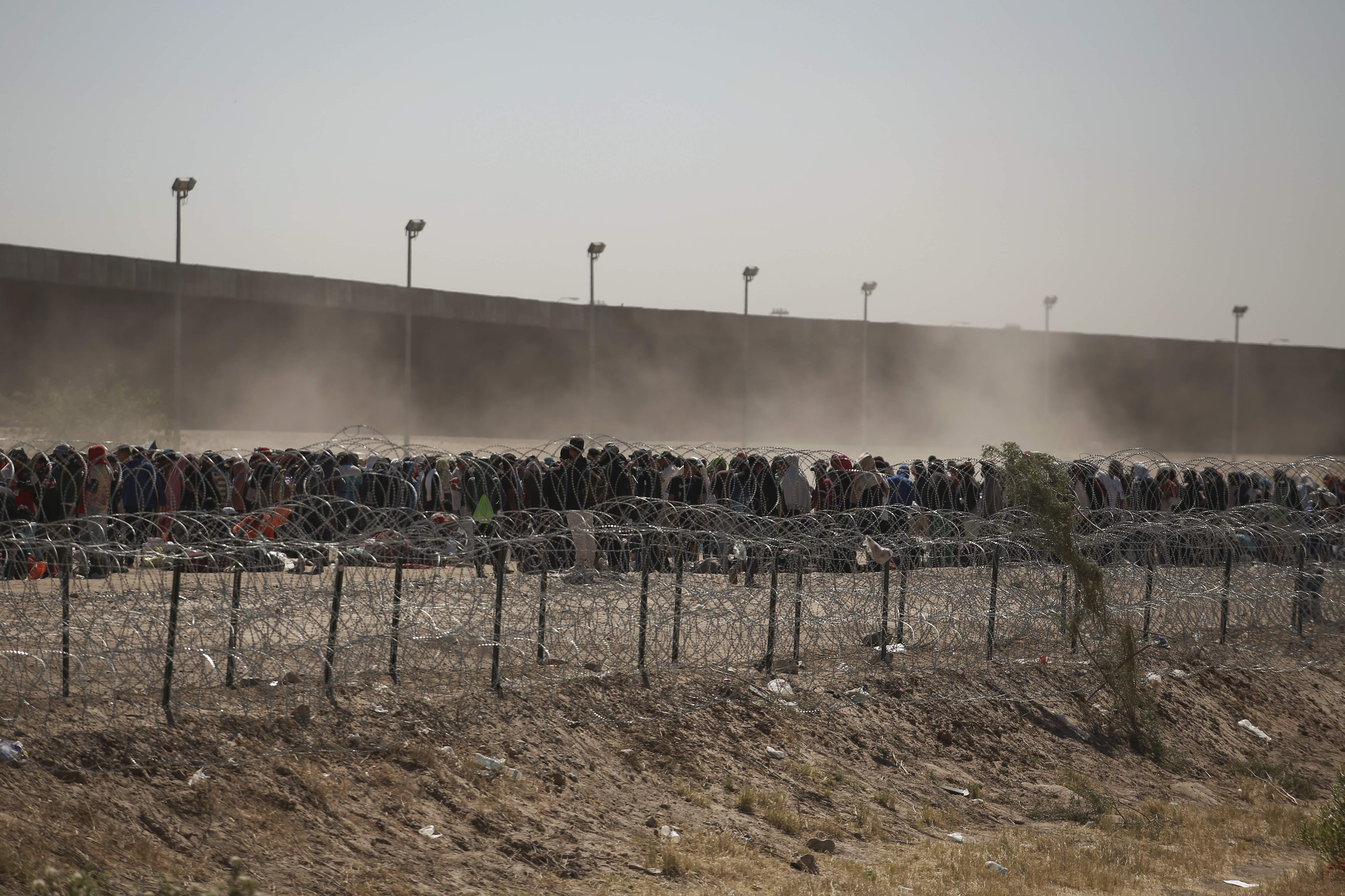 Migrants line up between a barbed-wire barrier and the border fence at the U.S.-Mexico border, as seen from Ciudad Juarez, Mexico, Tuesday. The U.S. is preparing for the Thursday end of the Title 42 policy, linked to the coronavirus pandemic that allowed it to quickly expel many migrants seeking asylum.