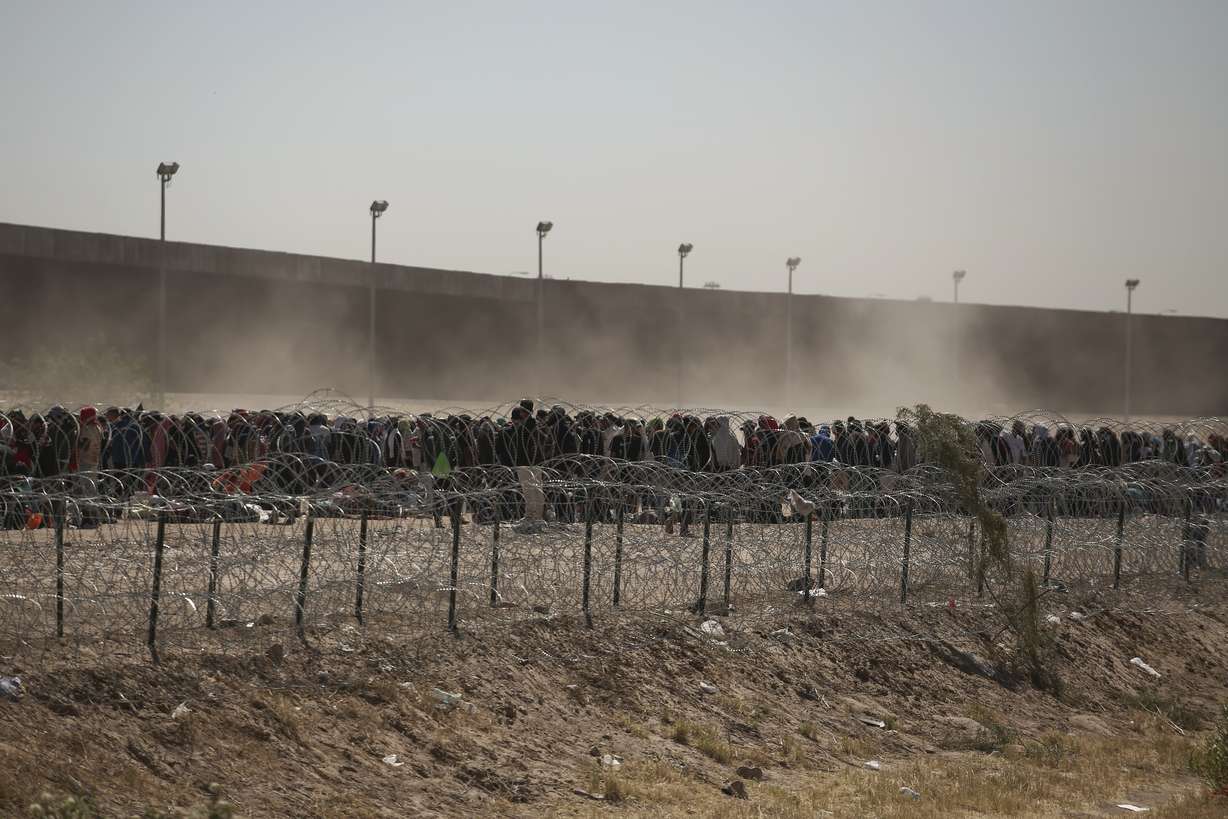 Migrants line up between a barbed-wire barrier and the border fence at the U.S.-Mexico border, as seen from Ciudad Juarez, Mexico, Tuesday. The U.S. is preparing for the Thursday end of the Title 42 policy, linked to the coronavirus pandemic that allowed it to quickly expel many migrants seeking asylum.
