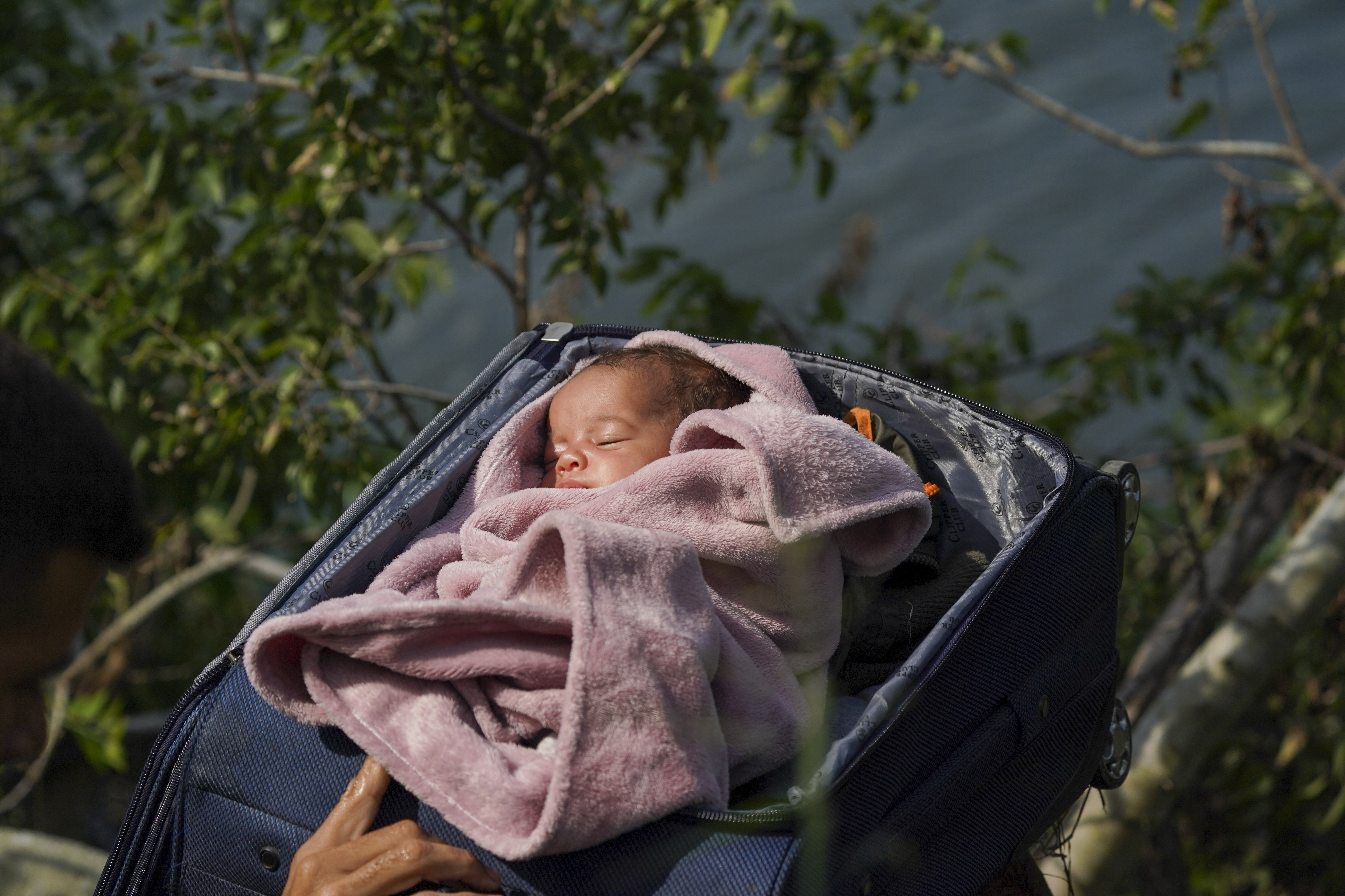 Migrants cross the Rio Grande into the U.S. with a baby in a suitcase, as seen from Matamoros, Mexico, Wednesday. Asylum seekers have been showing up at the US-Mexico border in huge numbers in anticipation of the restriction of Title 42 Thursday.
