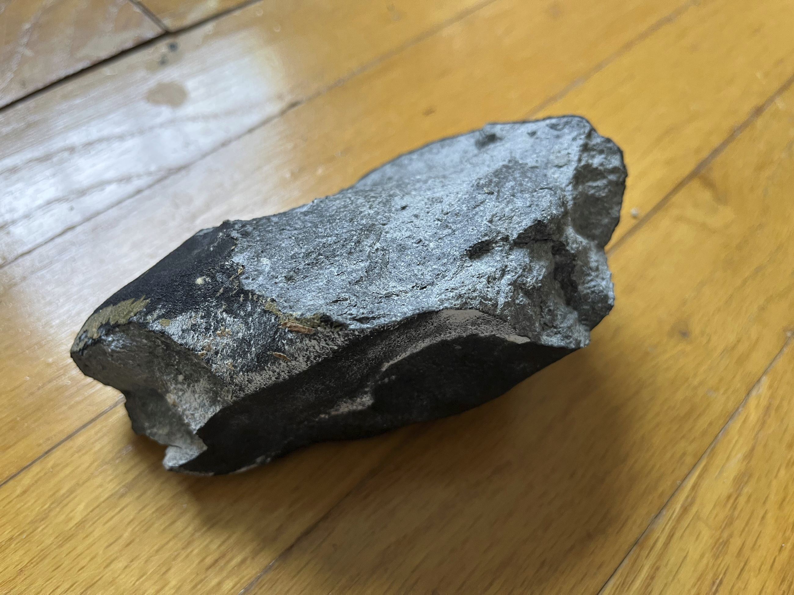 This image shows a confirmed meteorite on a hardwood floor at a residence in Hopewell Township, N.J. The meteorite punched a hole in the roof of the central New Jersey home.