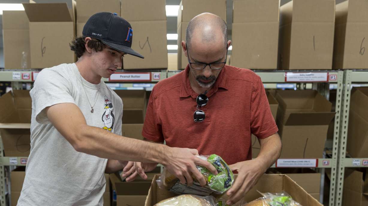 Alex Puccio volunteers with his father, Rick Puccio, at the Utah Food Bank in Salt Lake City on Oct. 3, 2022. Utahns can place a bag of nonperishable food next to their mailbox by 9 a.m. on Saturday for the 31st Stamp Out Hunger Food Drive.