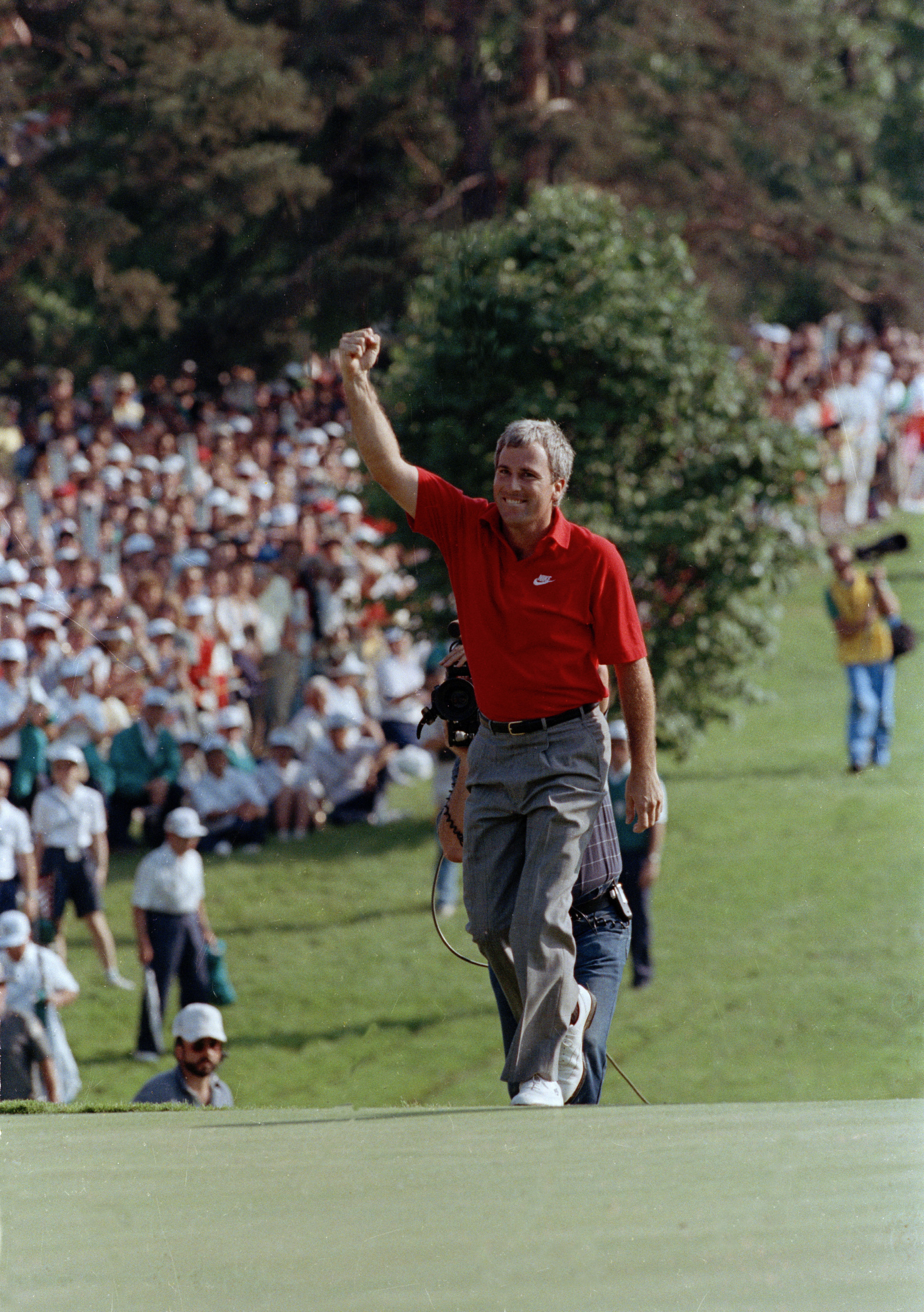 FILE- Curtis Strange reaches the 18th green waving to the crowd as he is about to win the U.S. Open for the second straight year, June 18, 1989, at the Oak Hill Country Club in Rochester, N.Y. Strange returns to Oak Hill for the PGA Championship on May 18-21 as part of the ESPN broadcast team. 