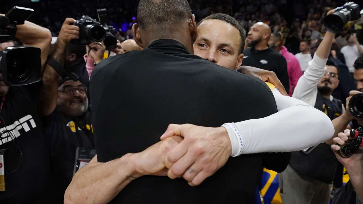 Los Angeles Lakers forward LeBron James, back to camera, hugs Golden State guard Stephen Curry after Game 6 of an NBA basketball Western Conference semifinal series Friday, May 12, 2023, in Los Angeles. Los Angeles won 122-101 to take the series and advance to the conference championship.